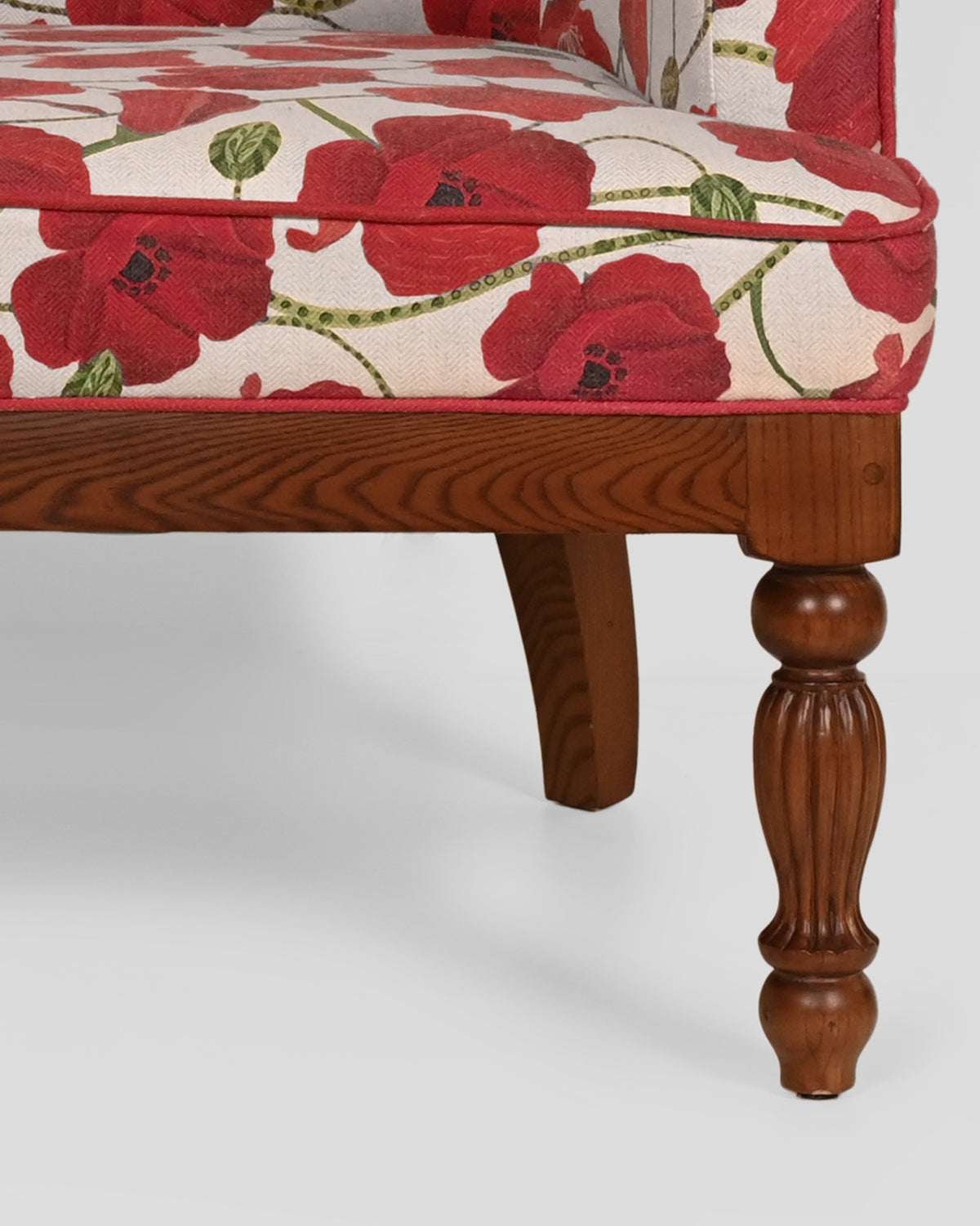 Close-up of the Meadow Chair's turned wooden leg and poppy upholstery.