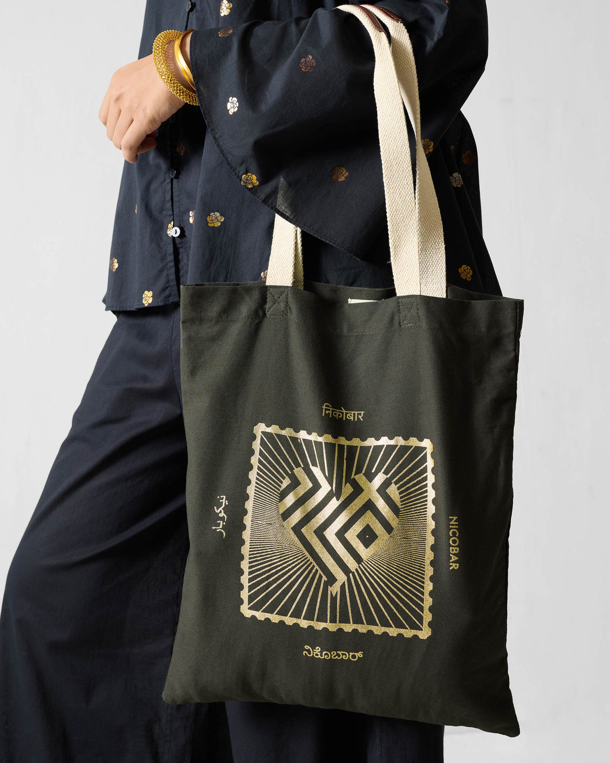 Person carrying a charcoal Road To 10 Tote with a gold stamp heart graphic.