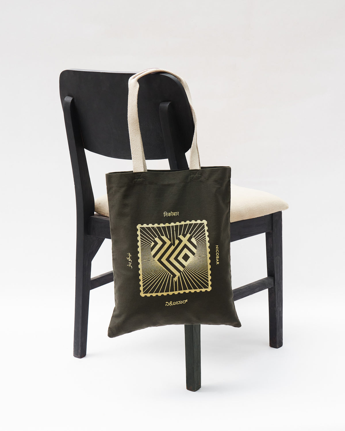 Charcoal Road To 10 Tote with a gold stamp heart hanging on a chair.