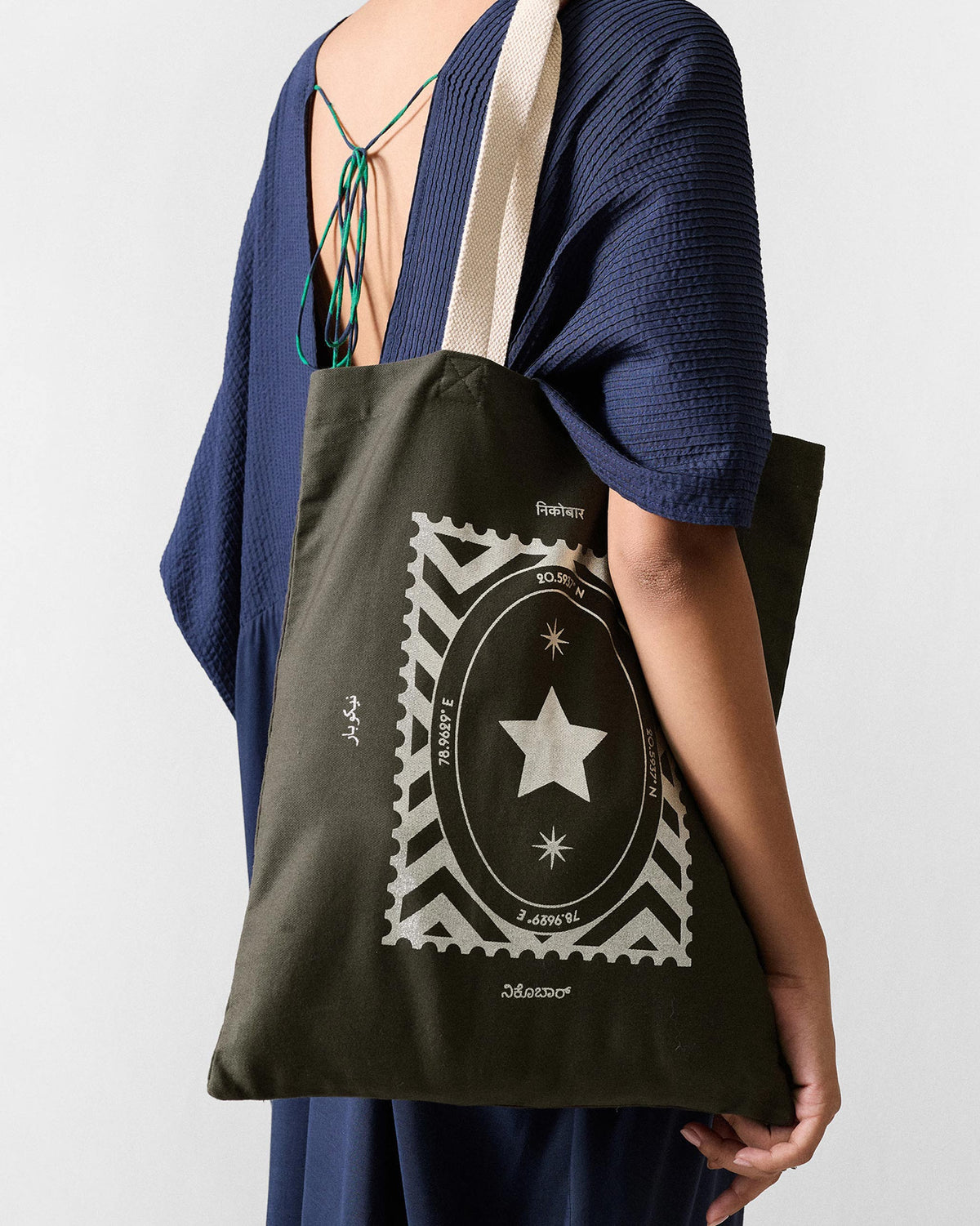 Charcoal Decade Tote with a silver stamp star print, worn on the shoulder.