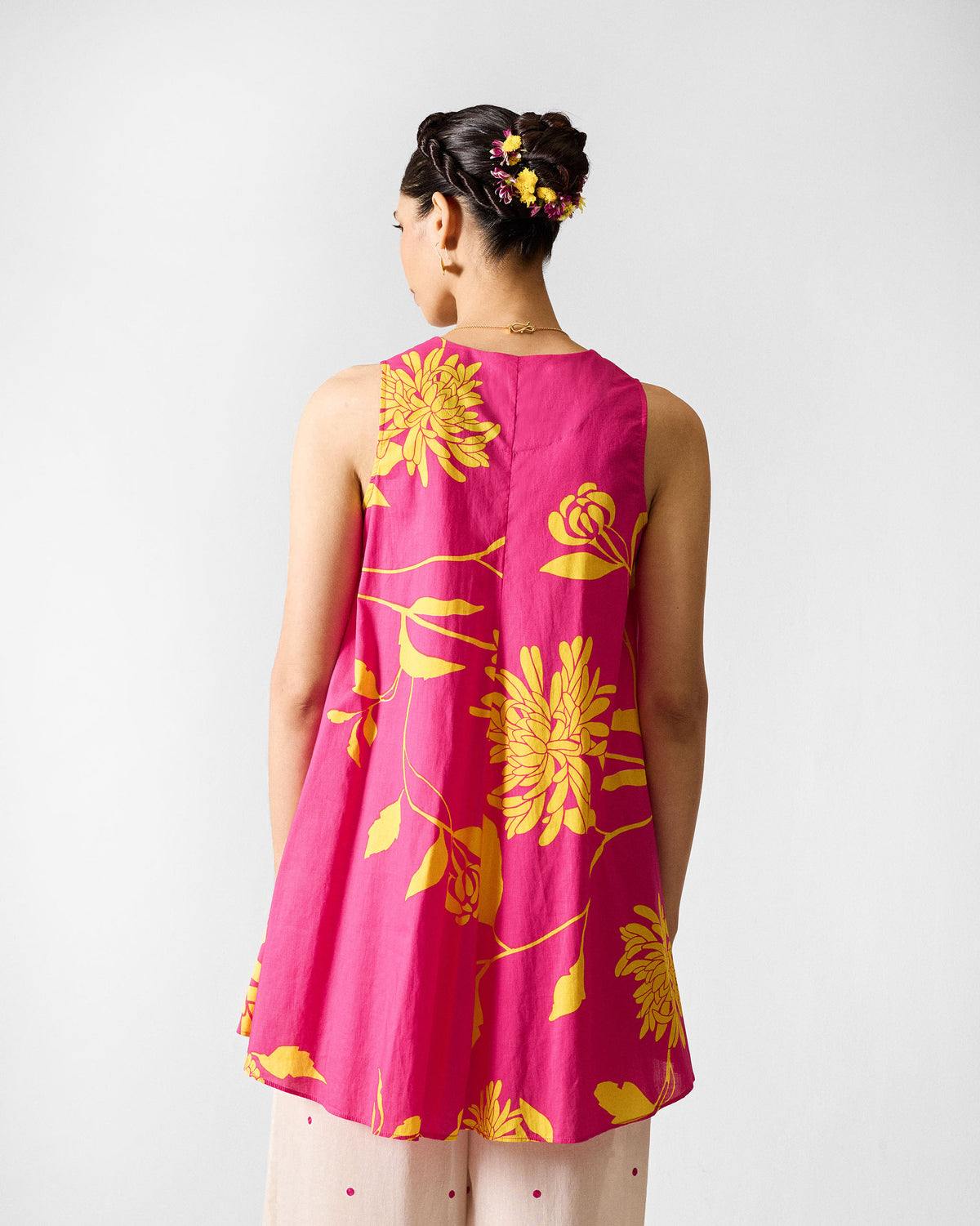 Back of a fuchsia lantern top with yellow floral print worn by a person.