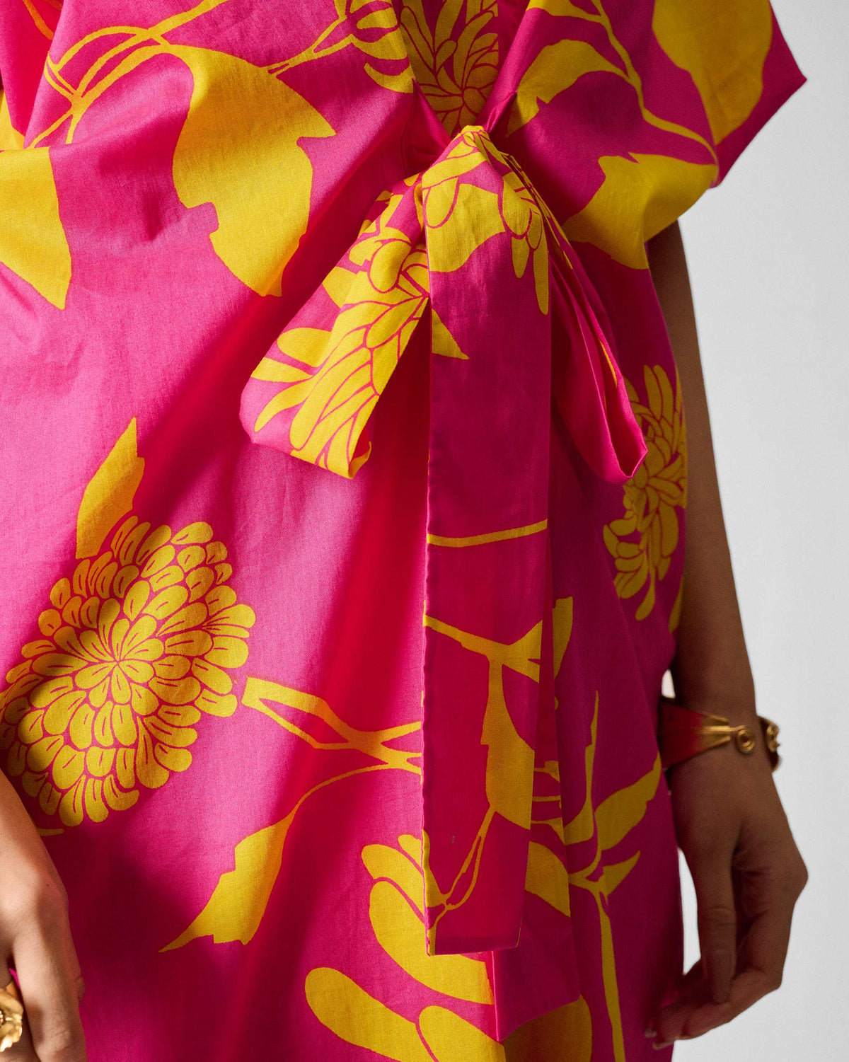 Close-up of the waist tie on a fuchsia Doda dress with lime florals.