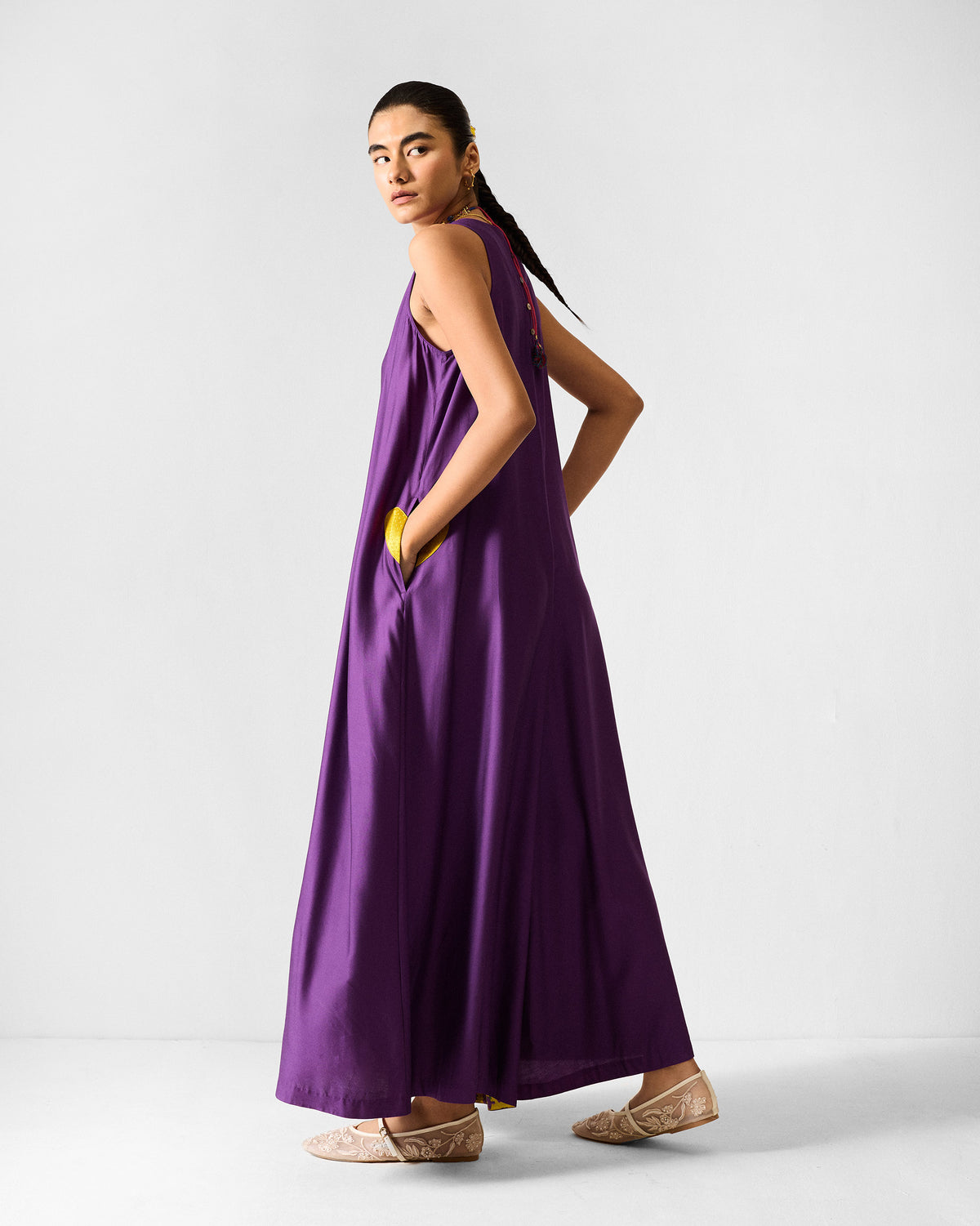 Back of a purple Amreli jumpsuit with lime yellow pocket lining.