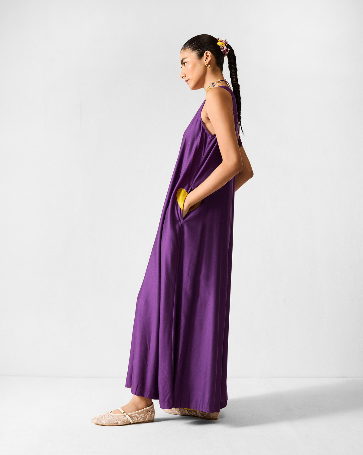 Side view of a purple Amreli jumpsuit with a yellow heart at the pocket.