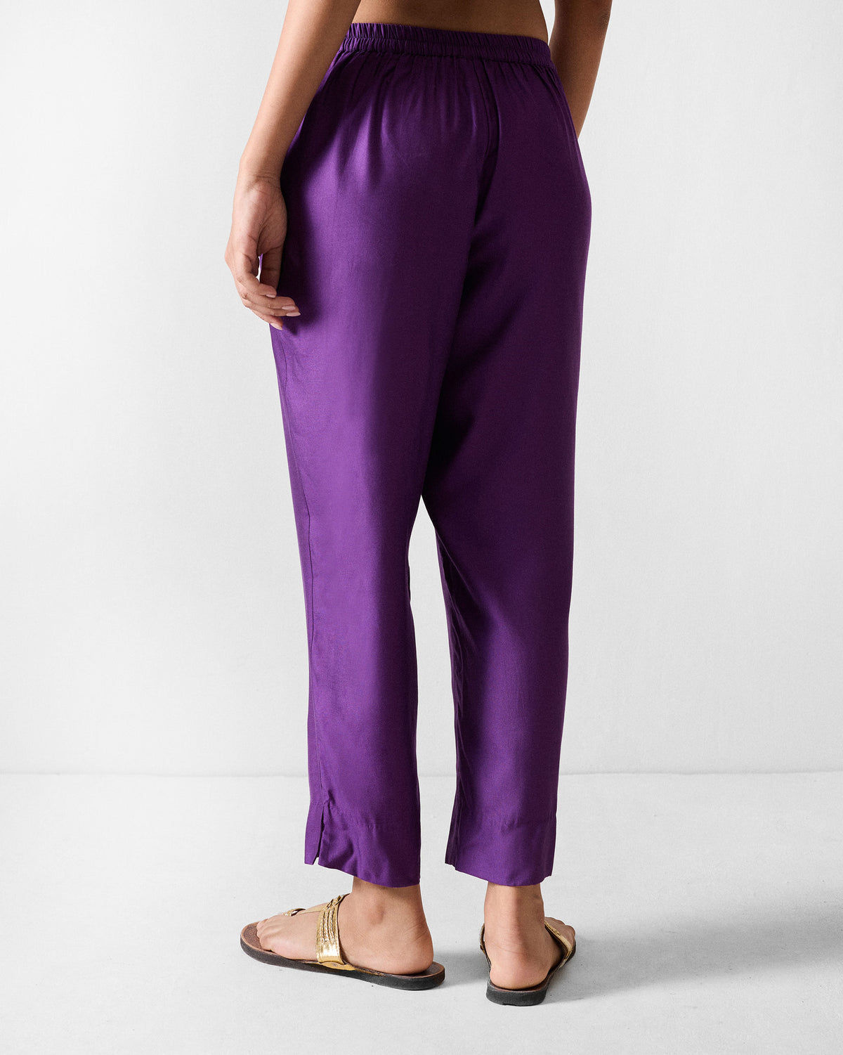 Back of purple Darjeeling pants with a gathered waistband and ankle side slits.