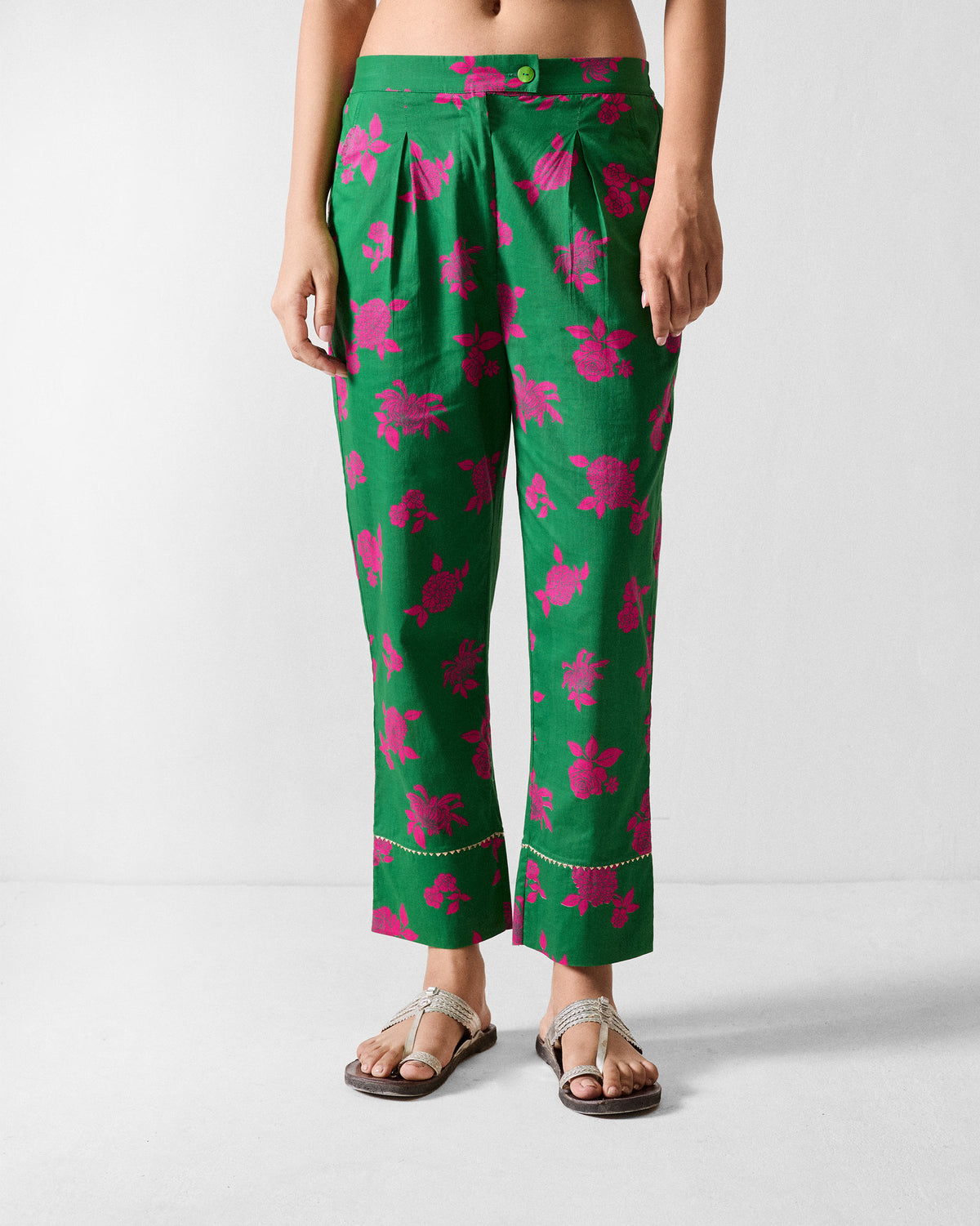 Person wearing green printed Novel narrow pants with pink florals and gold trim near the hem.