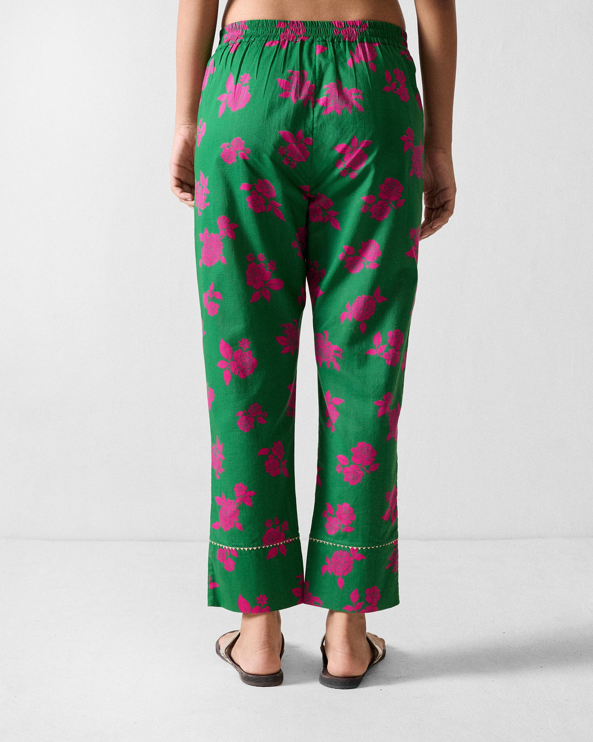 Back of green printed Novel narrow pants with pink florals and gold trim near the hem.