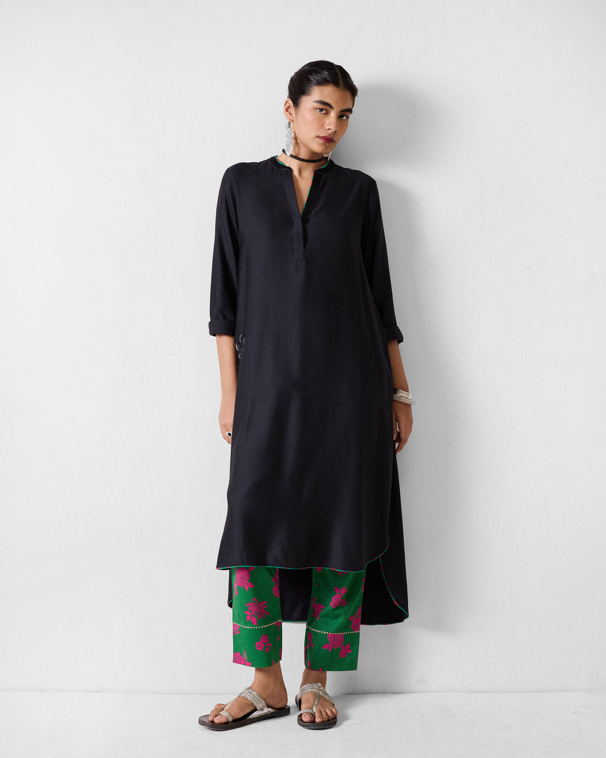 Person wearing green printed Novel narrow pants with pink florals and gold hem trim.