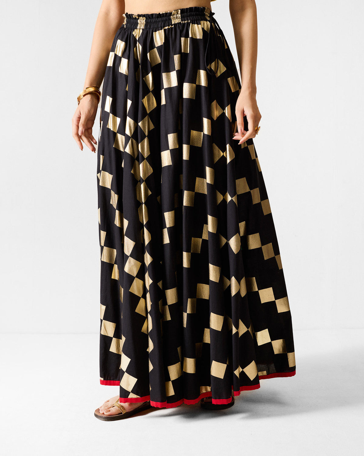 Person wearing a black Afsar Skirt with a gold square foil print.