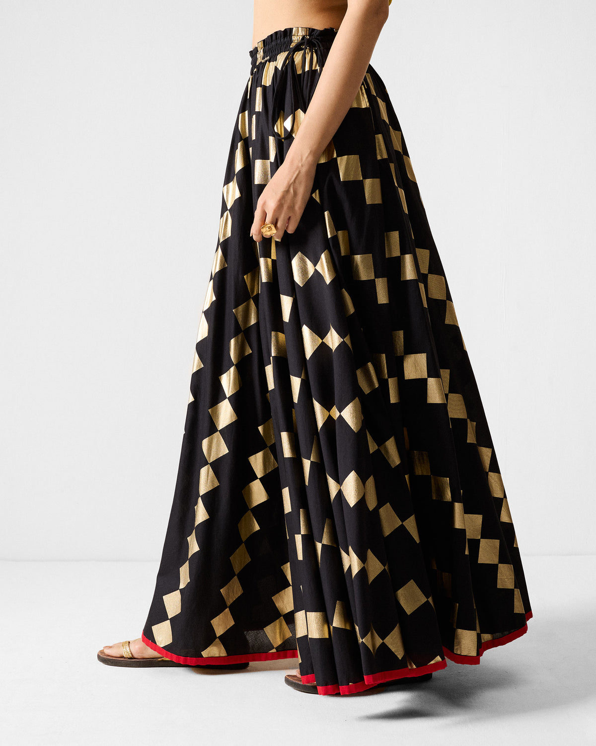 Side view of a black Afsar Skirt with gold foil print and drawstring waist.