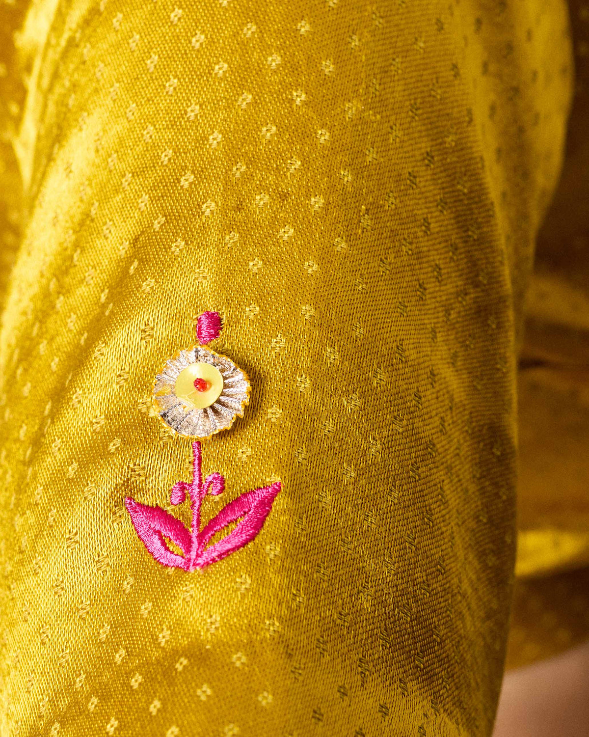 Close-up of a Dori blouse sleeve with a pink embroidered flower.