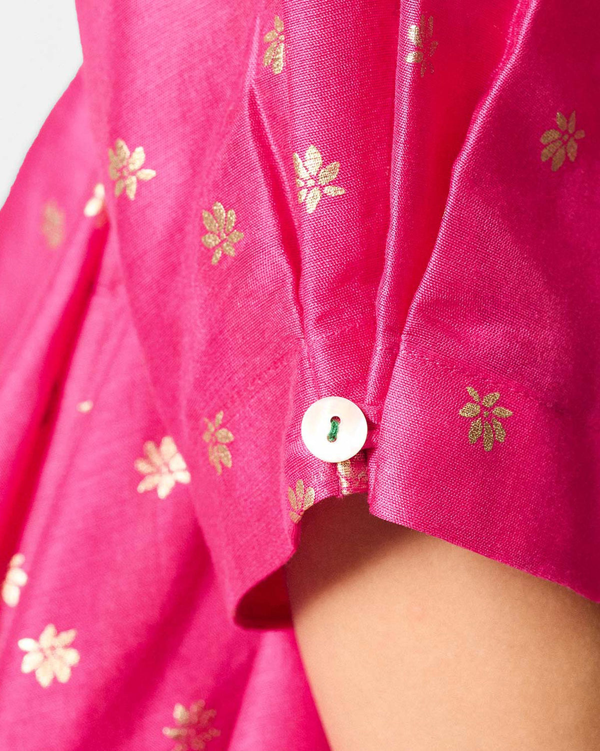 Close-up of a fuchsia Kannauj Kurta showing gold floral prints and a cuff button.