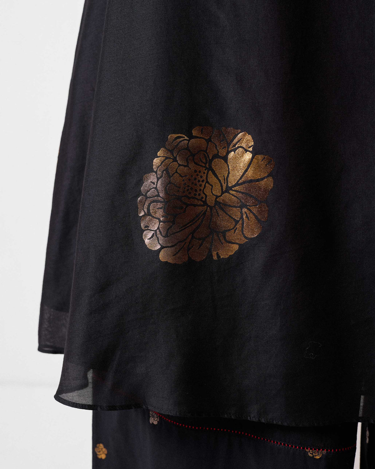 Close-up of a gold foil floral motif on a black boat-neck kurta.