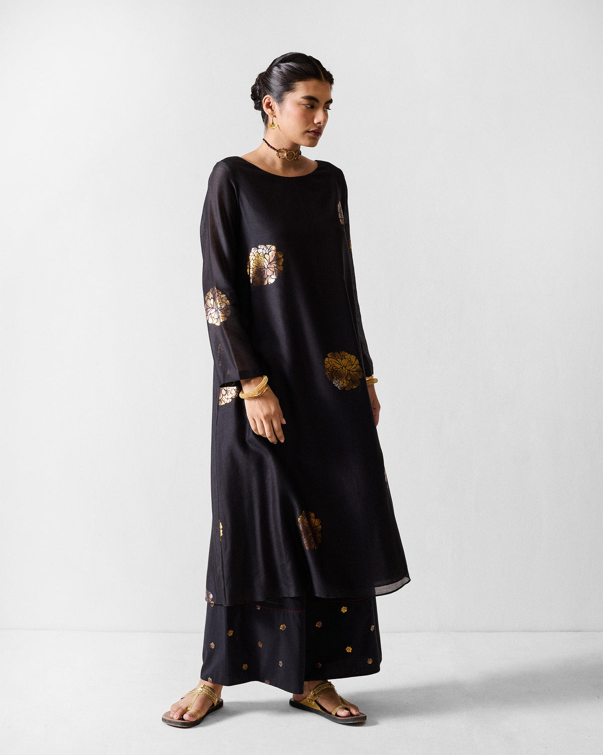 Person wearing a black boat-neck kurta with large gold foil florals.