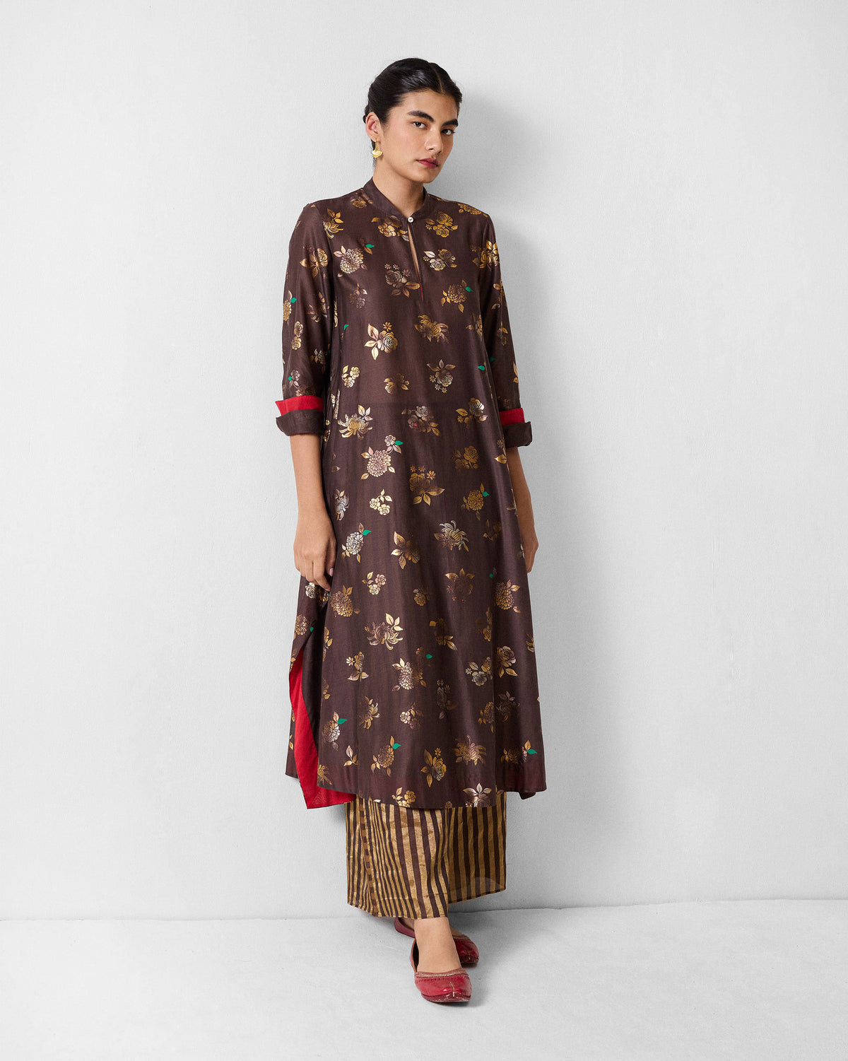 Person wearing a chocolate brown kurta with a gold floral print.