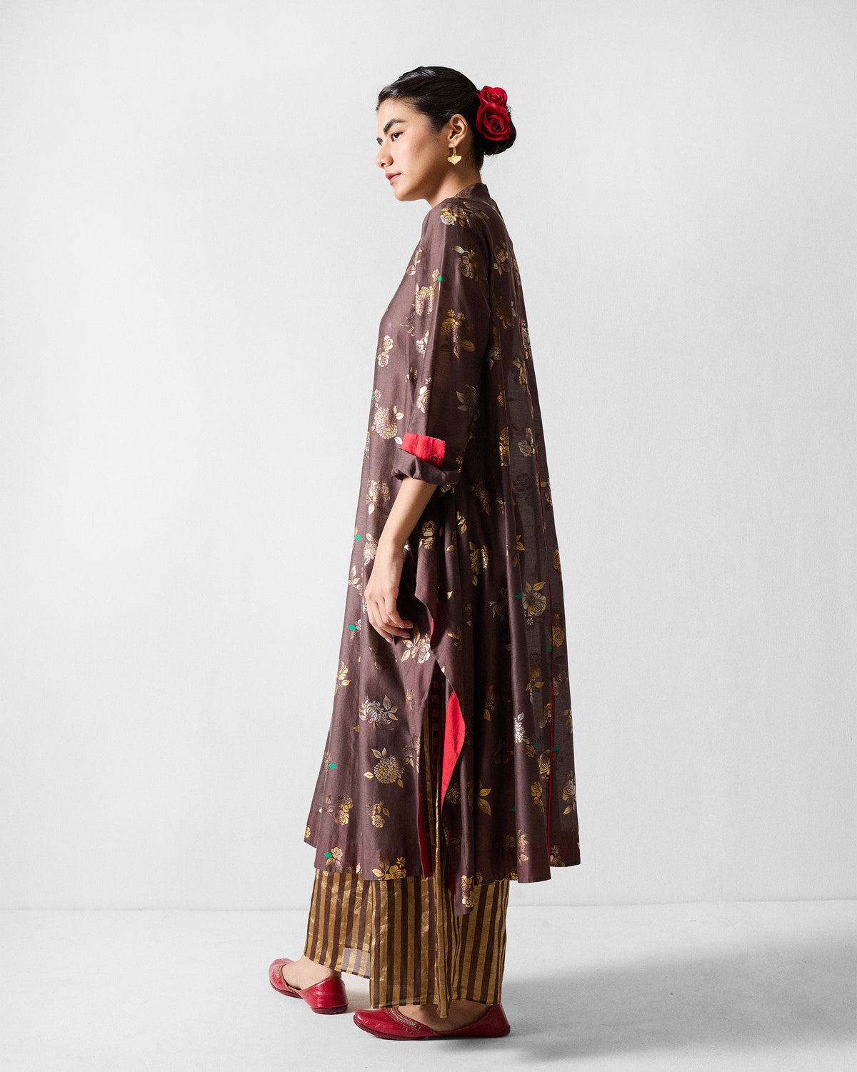 Person wearing a brown gold-print kurta with a red side lining.