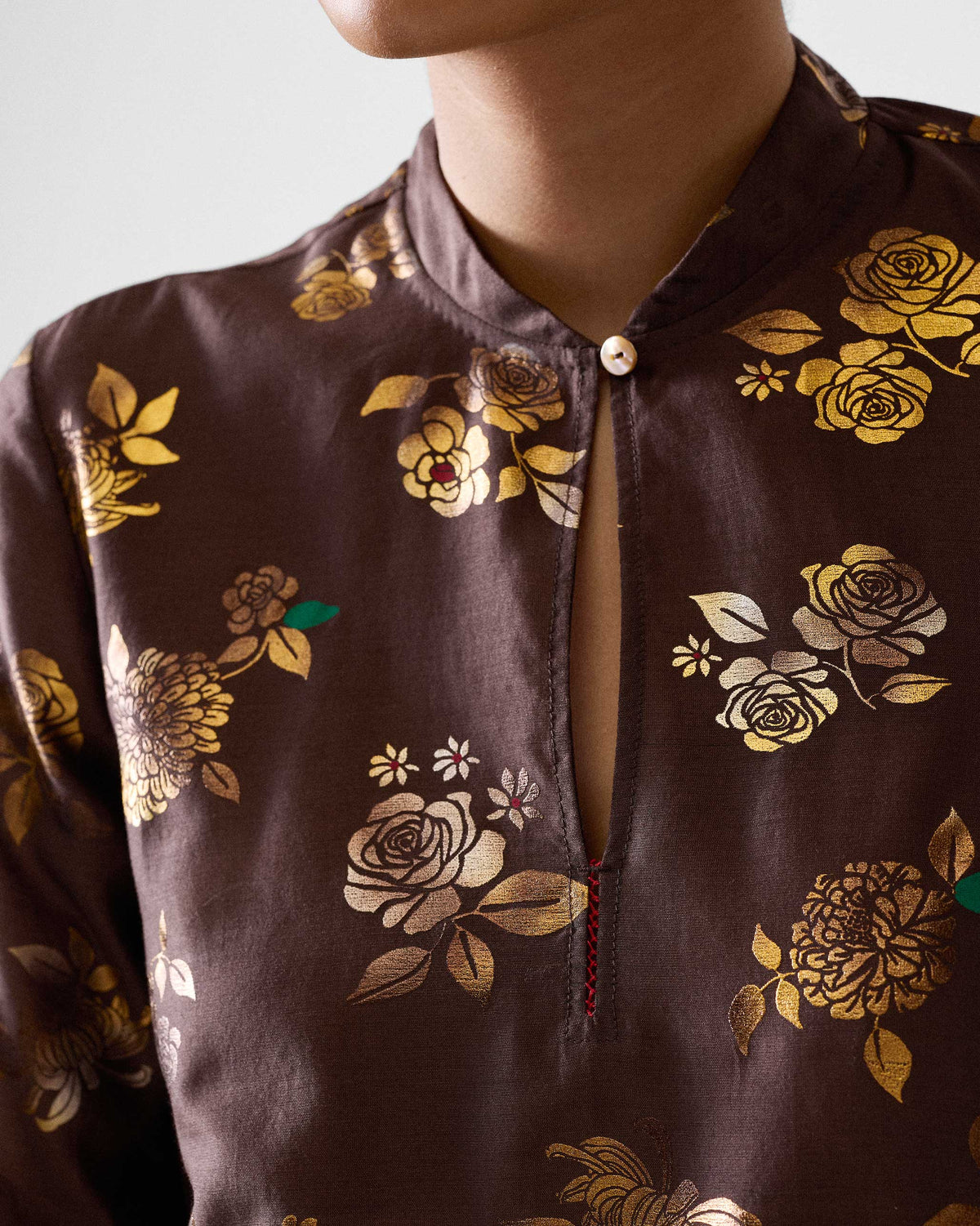 Close-up of a brown kurta with a gold floral print collar.