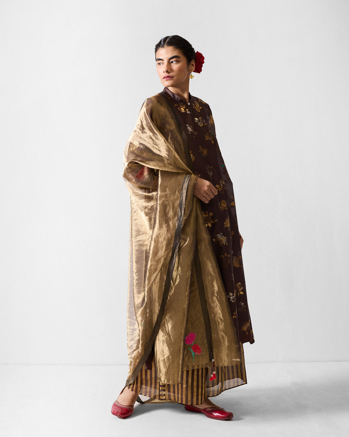 Person wearing a brown kurta with a gold floral print.