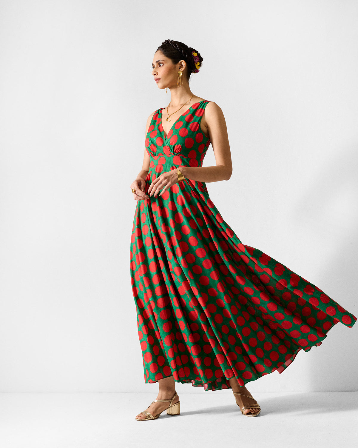 Person wearing a green maxi dress with large red polka dots.
