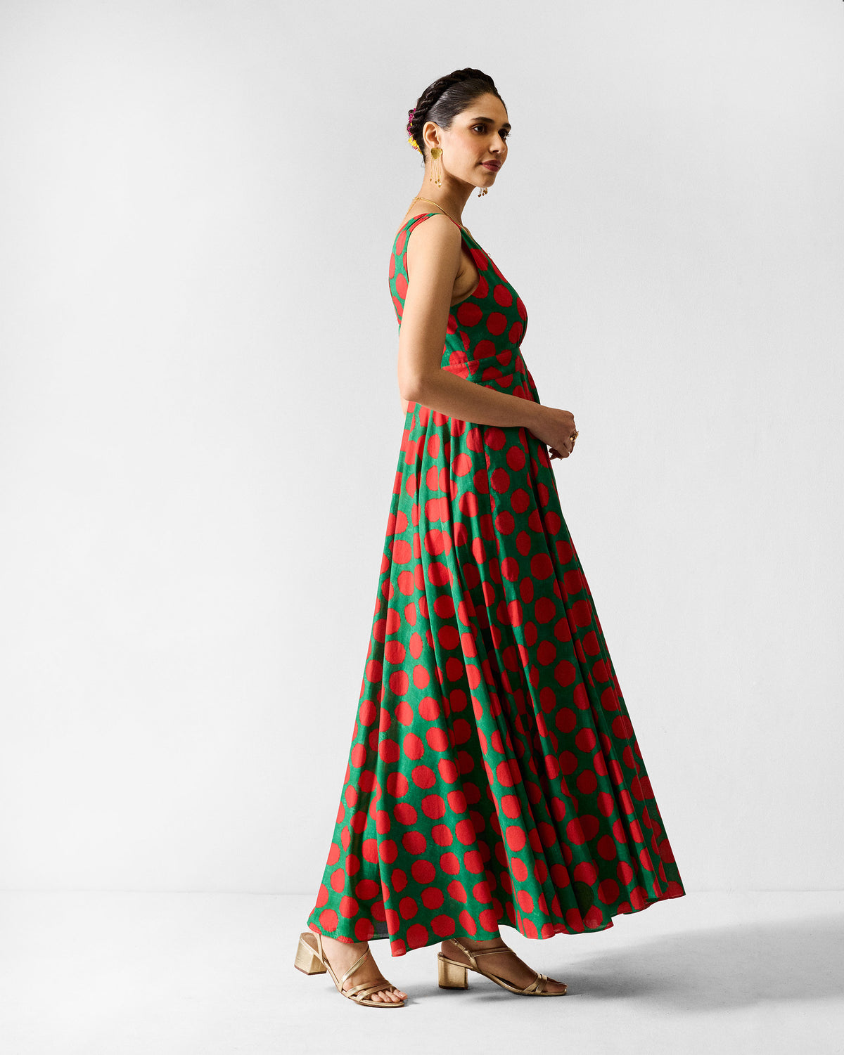Side view of a green Tribe dress with a flared skirt and red dots.