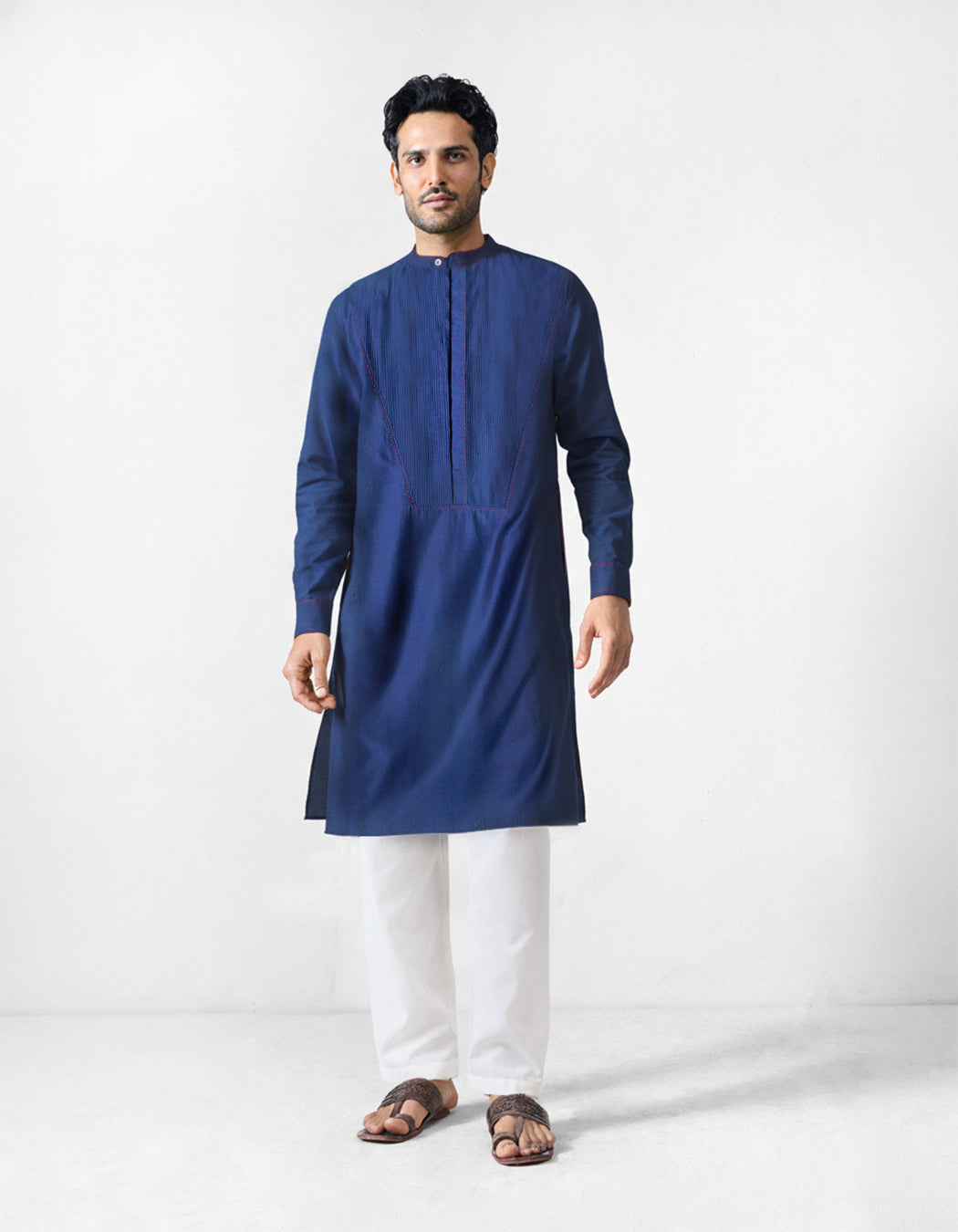 Navy Talha kurta worn full length with a pintuck bib panel.