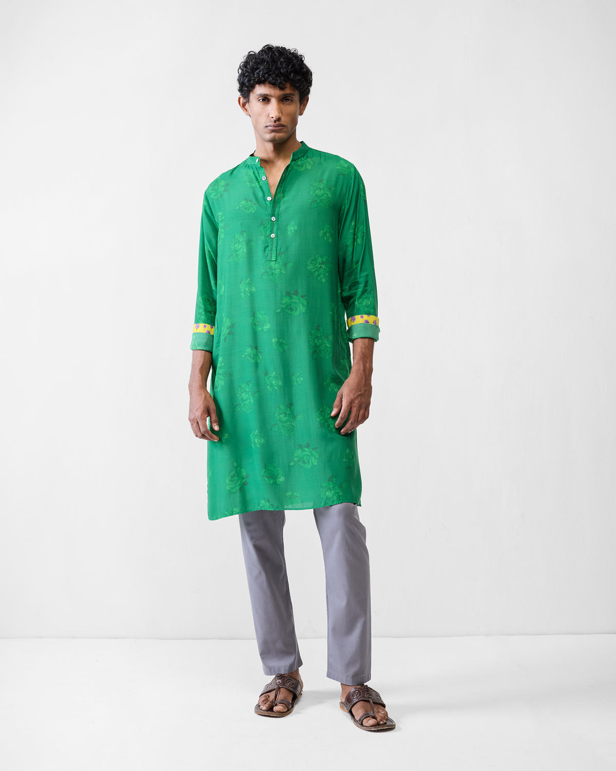 Person wearing an emerald green Astral kurta with yellow floral cuff linings.