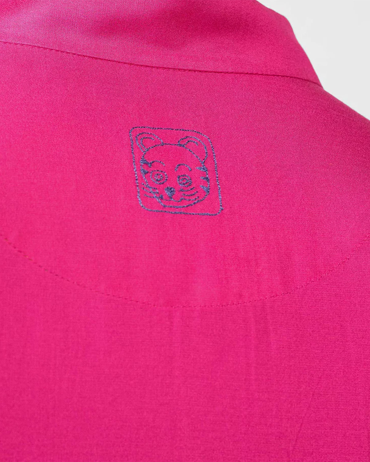 Close-up of a fuchsia Long pleated kurta collar with a blue embroidered emblem.