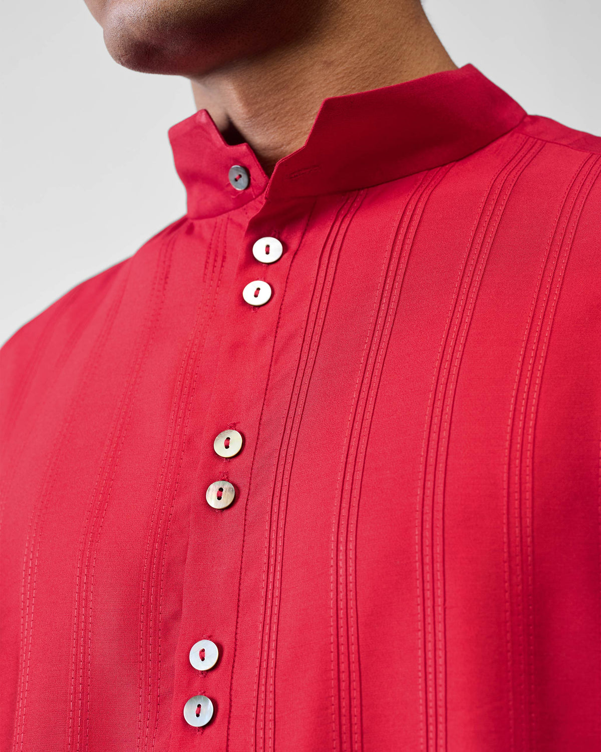 Close-up of a red Long Pleated Kurta with pintucks and paired pearl buttons.