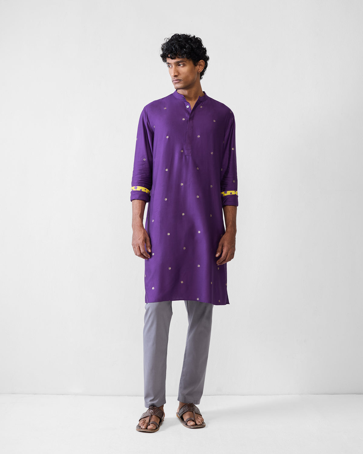 Person wearing a purple Neckband Kurta with rolled sleeves and gold motifs.
