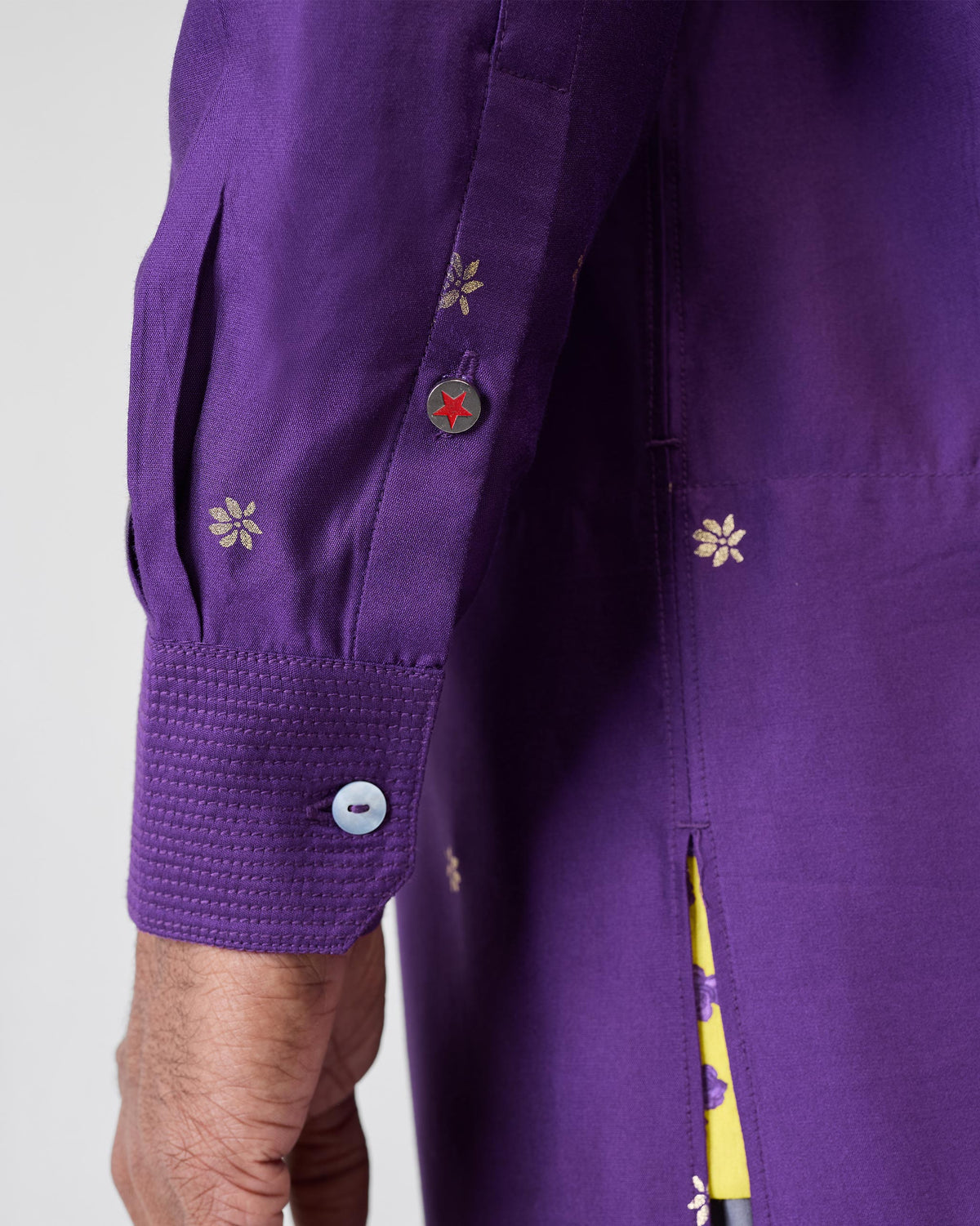 Close-up of a purple Neckband Kurta sleeve with a red star button.