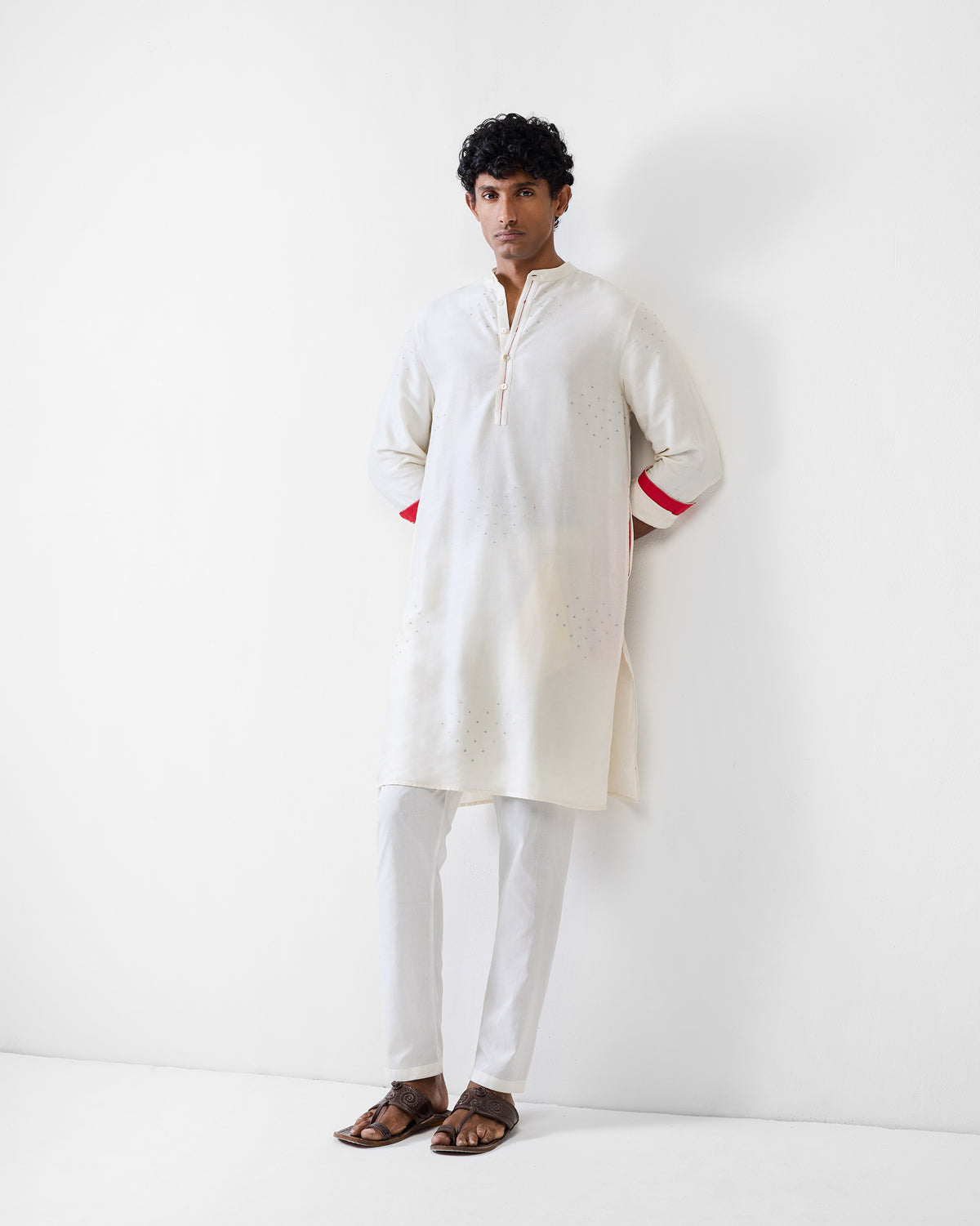 Person wearing an ivory astral kurta with silver hearts and red cuff lining.