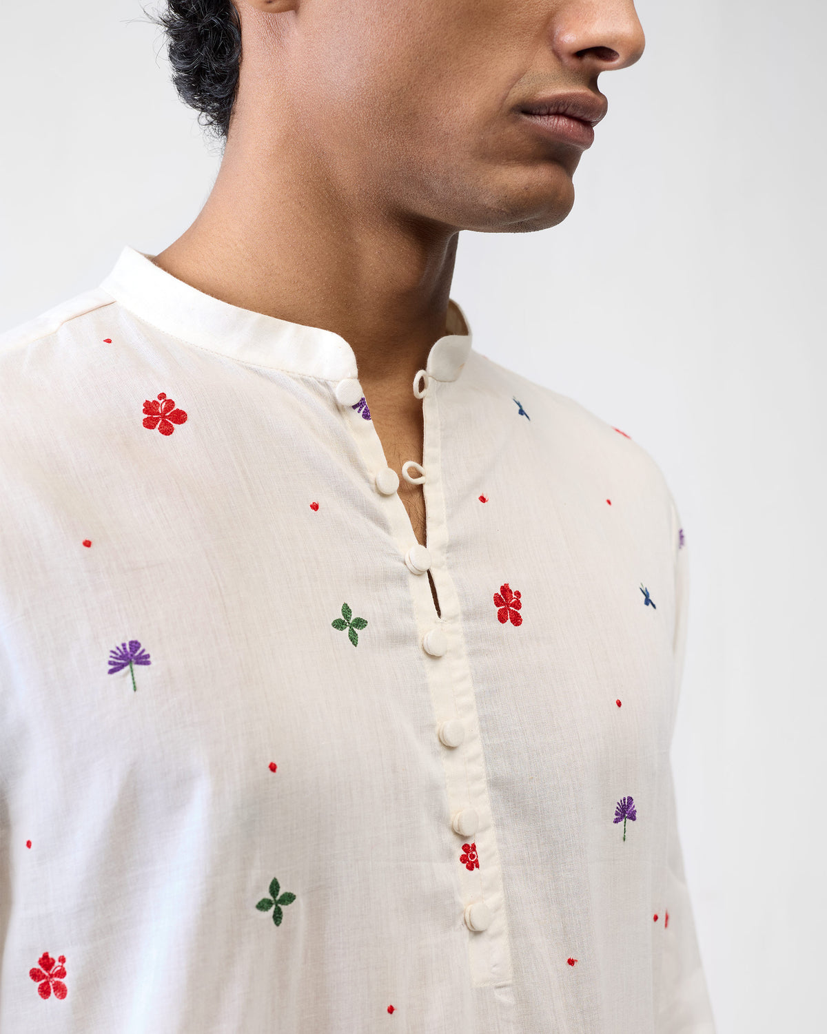 Close-up of an ivory Zenith Kurta showing hibiscus embroidery and band collar.