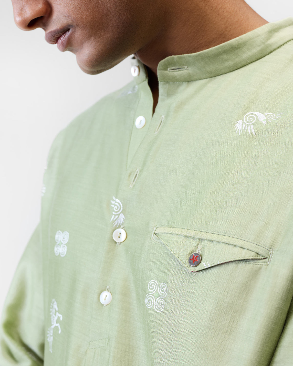 Close-up of a mint Fort kurta showing white motifs and a red-star pocket button.