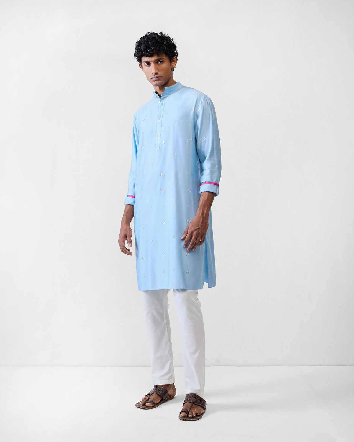 Person wearing a light blue embroidered Rey kurta with rolled sleeves.