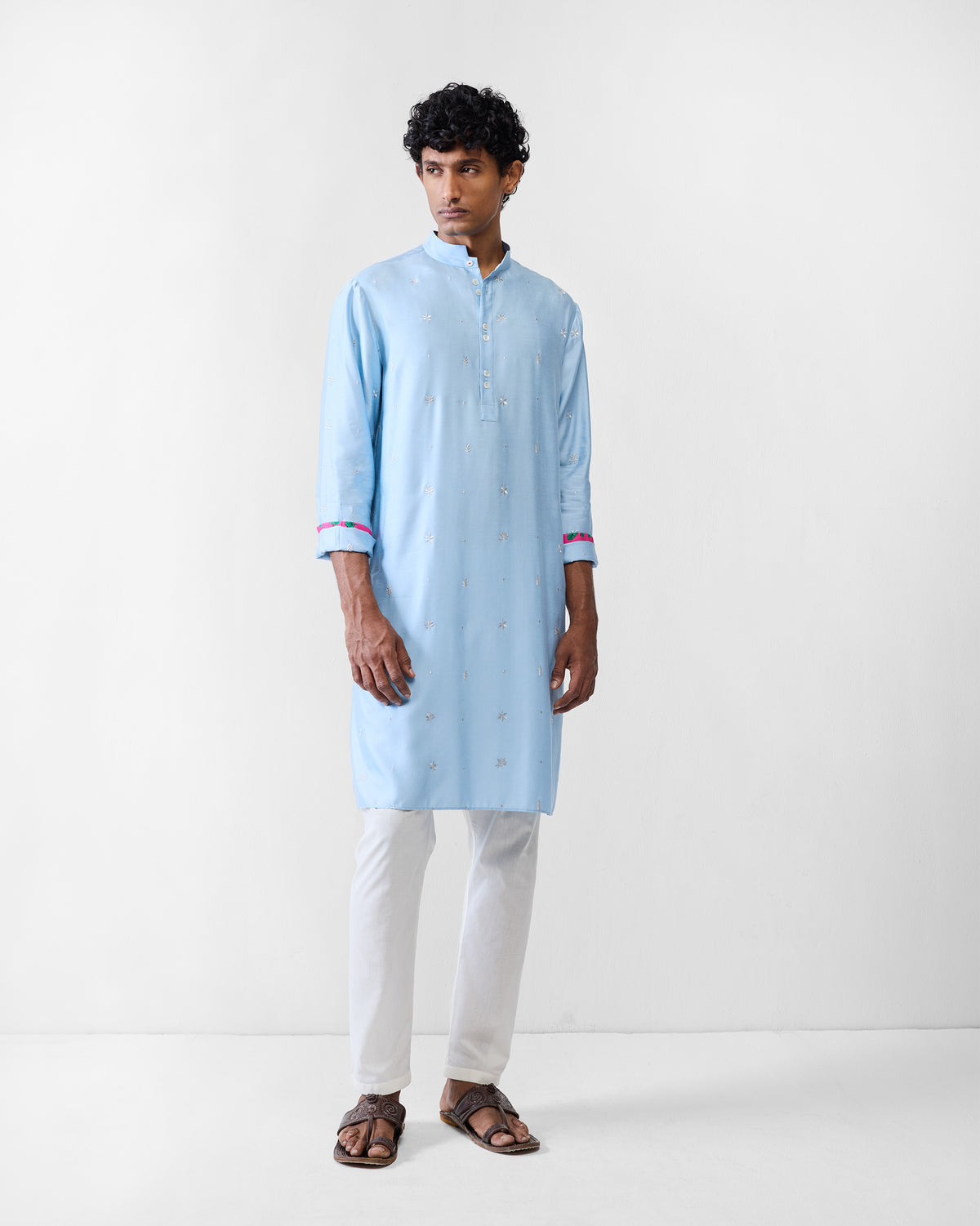Person wearing a light blue Rey kurta with embroidered motifs and cuff trim.