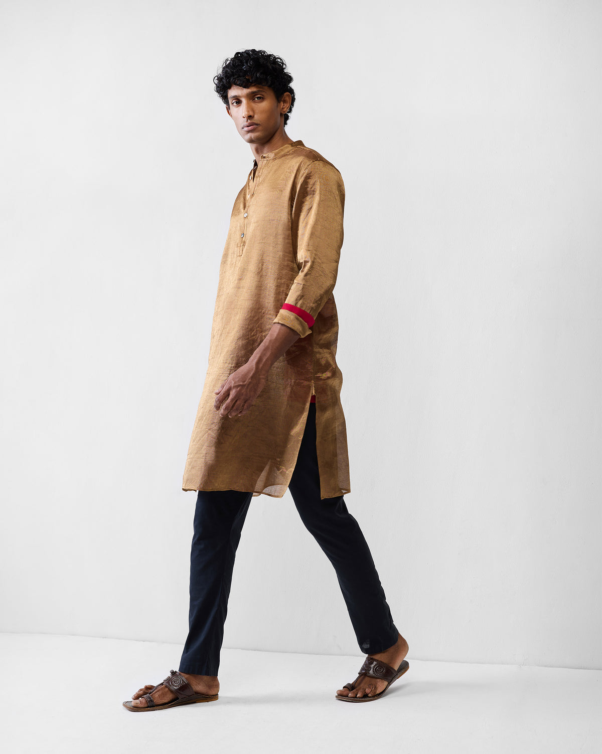 Side view of a gold Chandni Chowk kurta with red cuff lining.