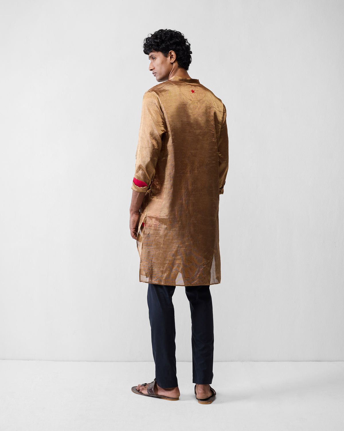 Back of a gold Chandni Chowk kurta with a red star.