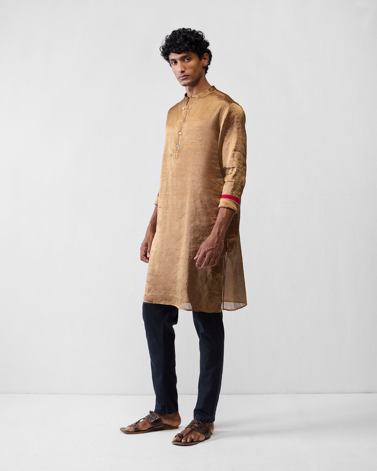 Person wearing a gold Chandni Chowk kurta with red cuff lining.