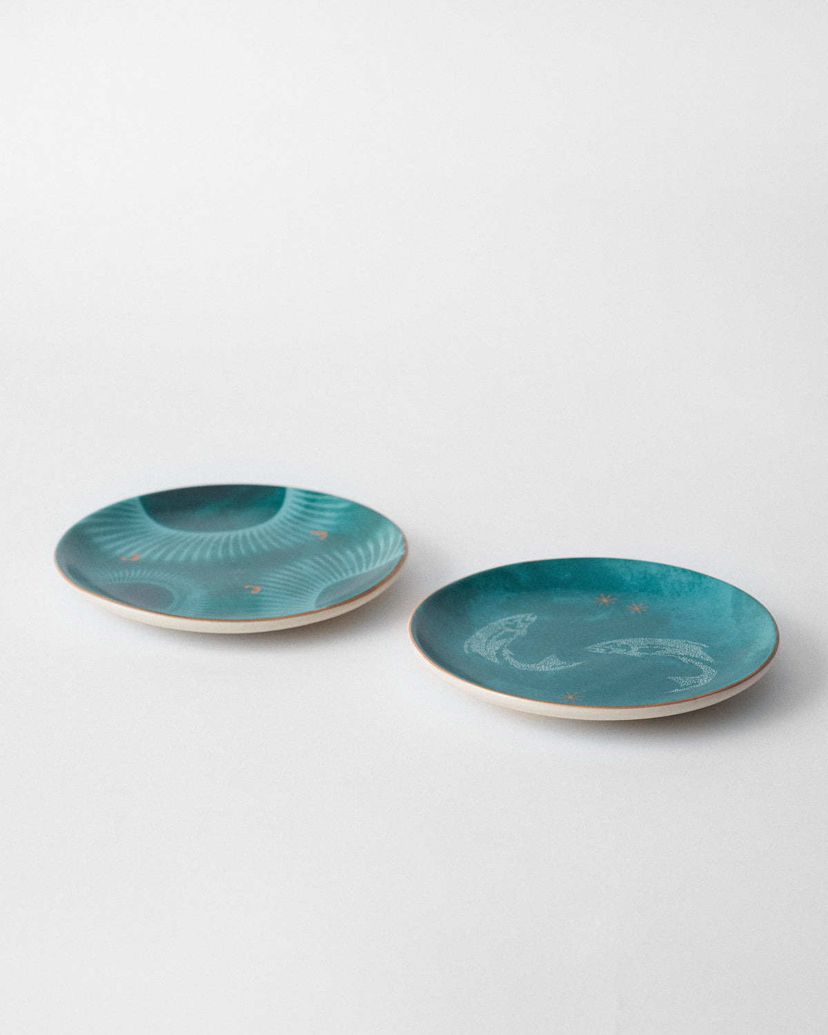 Pair of Caden quarter plates tilted to show teal faces and cream backs.