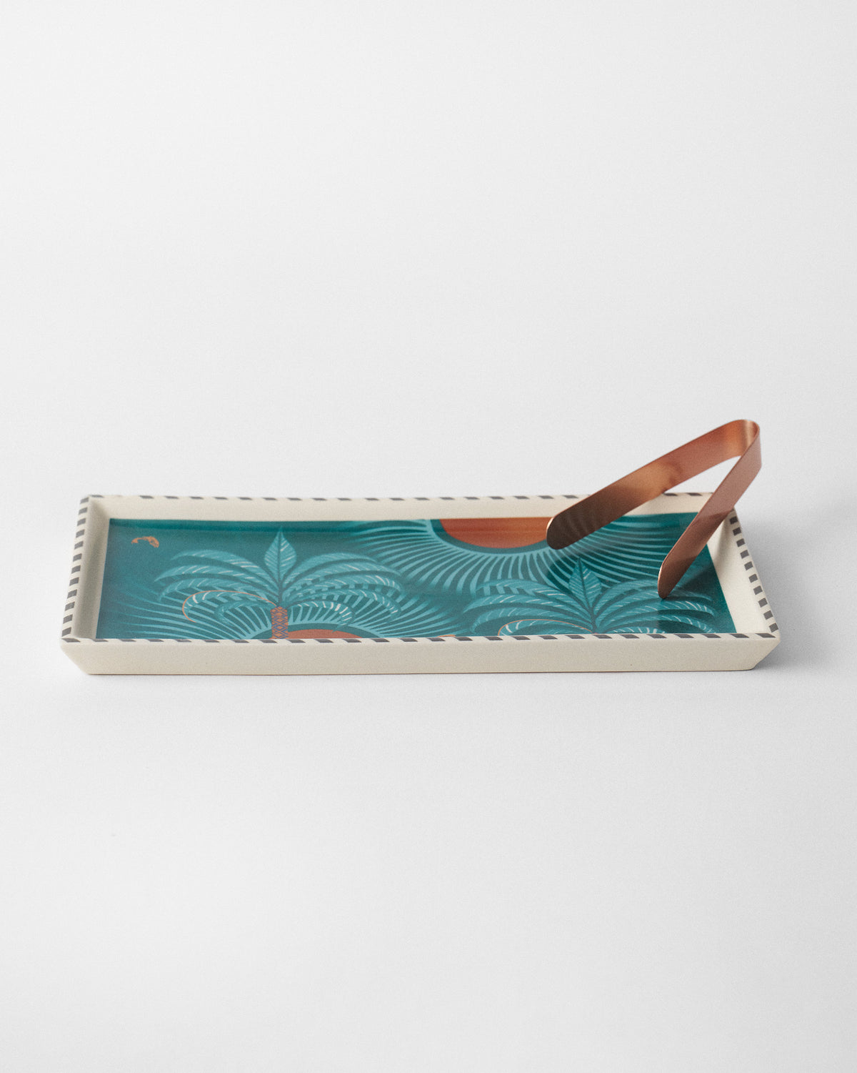 Caden cookie tray with teal palm print and copper tongs resting on top.