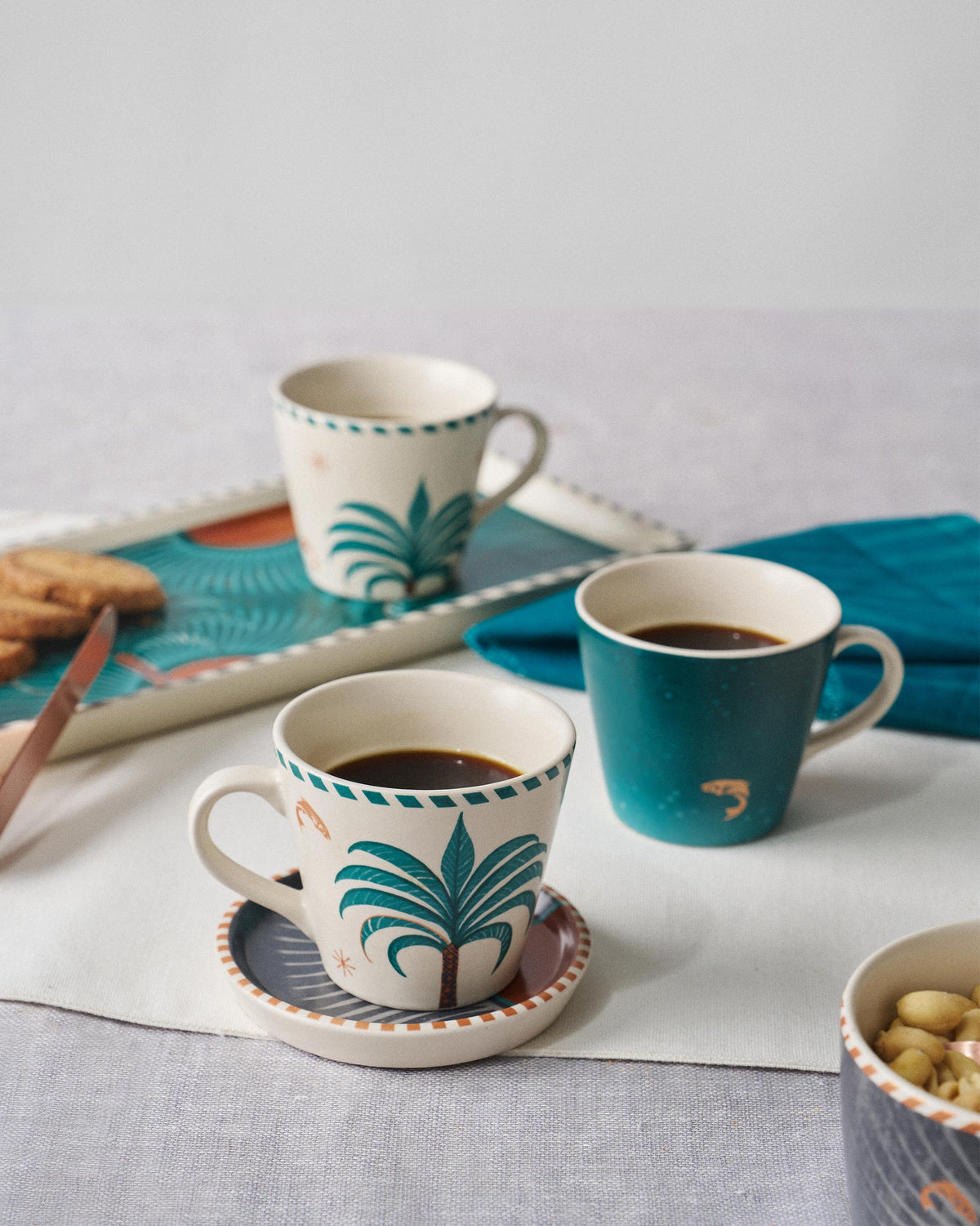 Aluna Espresso Mugs with palm-tree prints set on a breakfast table.