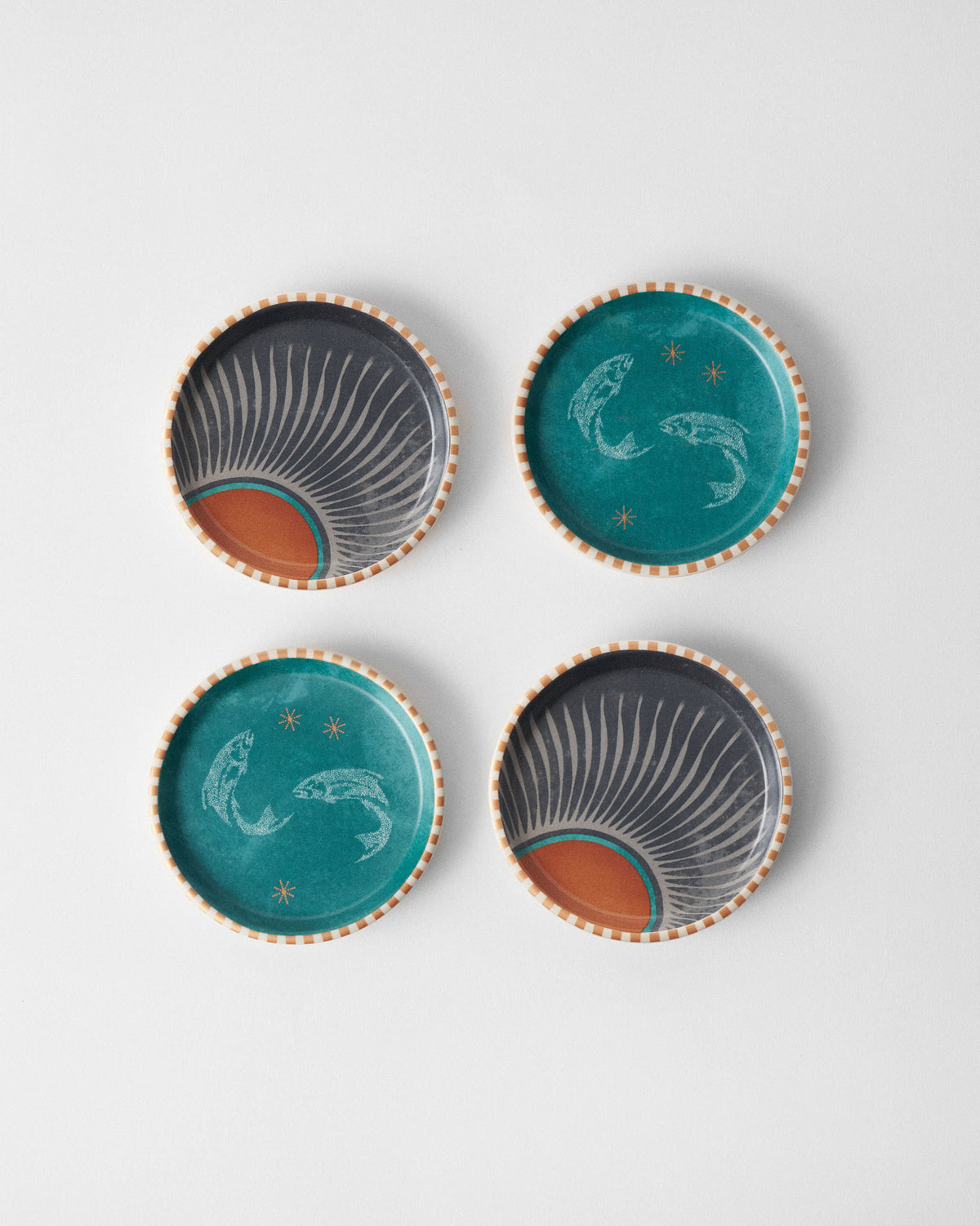 Set of four Aluna coasters with teal fish and charcoal sunburst designs.