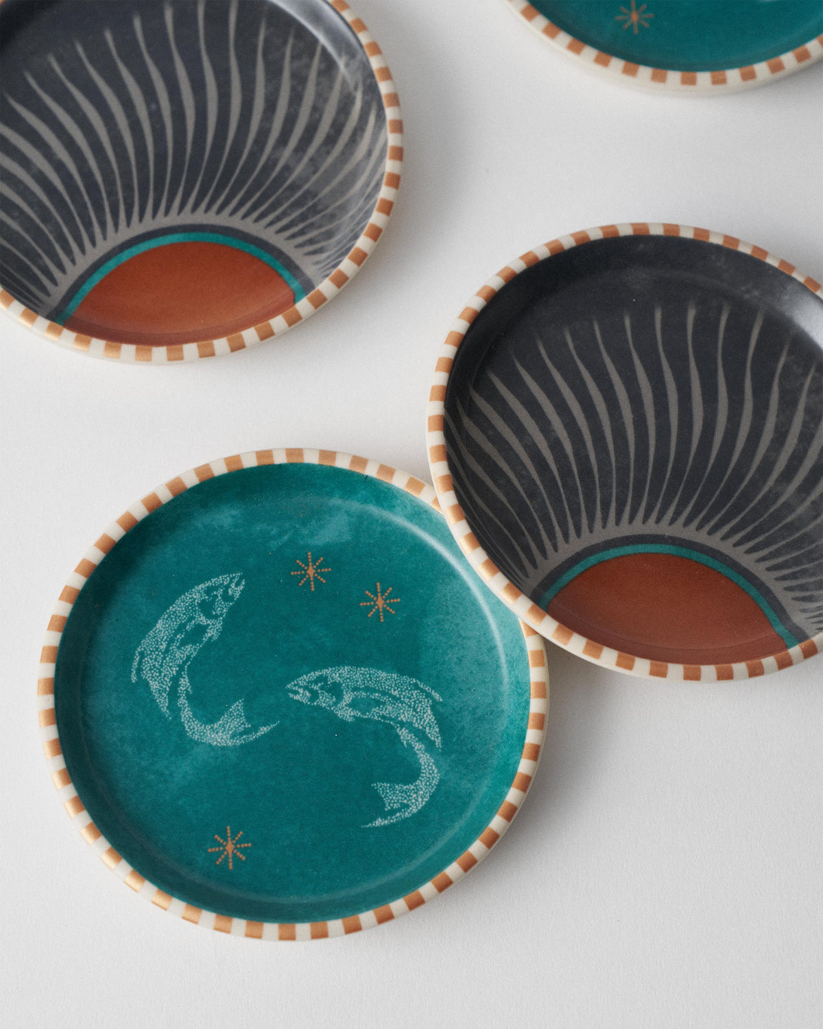 Close arrangement of Aluna coasters showing fish and sunburst motifs.