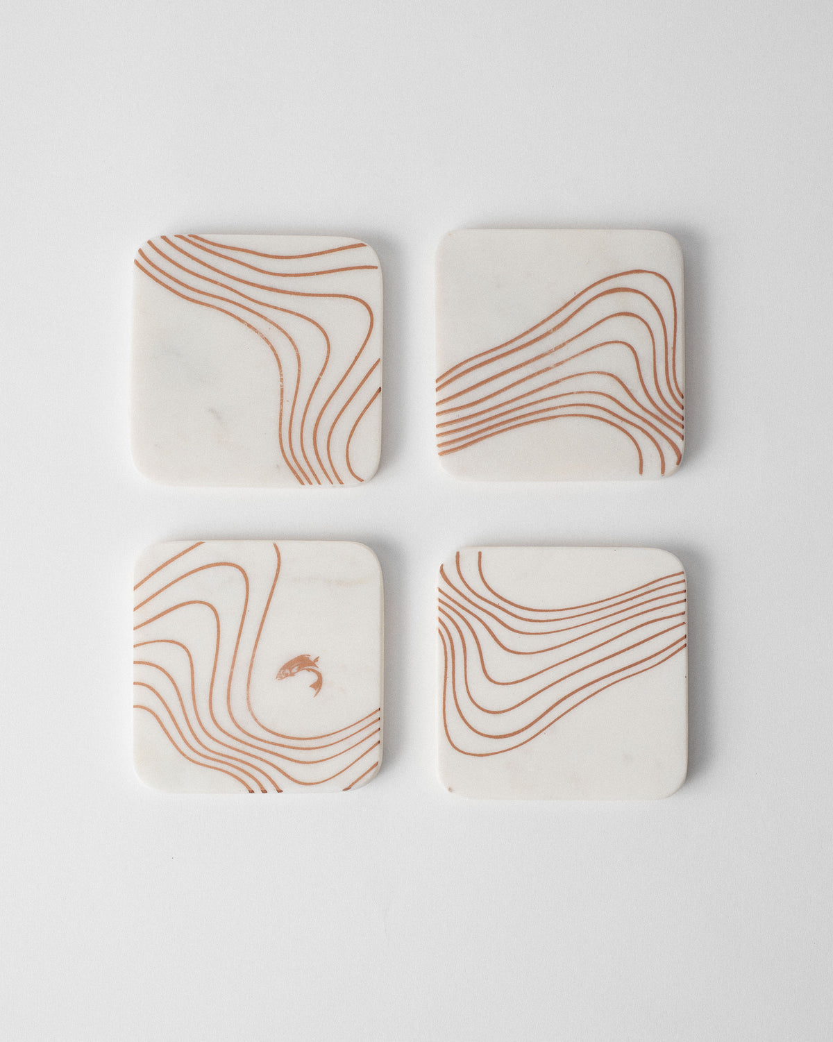 Set of four white marble Dusk coasters with copper wavy lines.