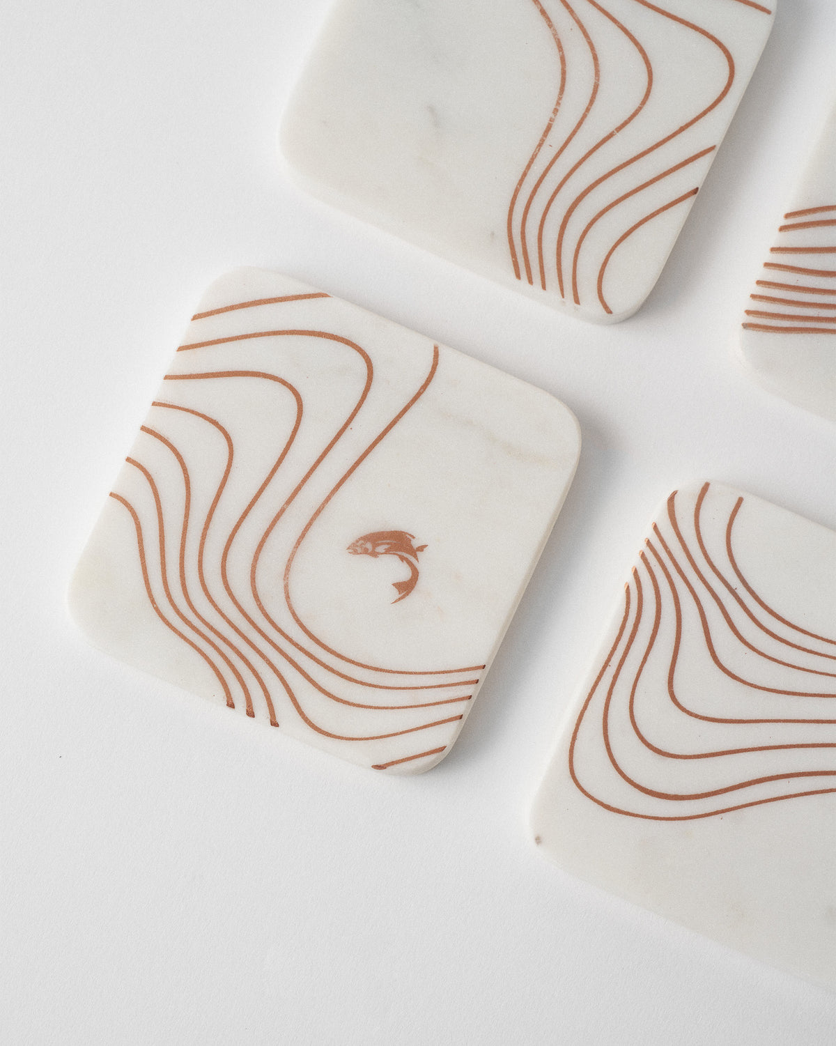 Close-up of a marble Dusk coaster with copper waves and a fish.