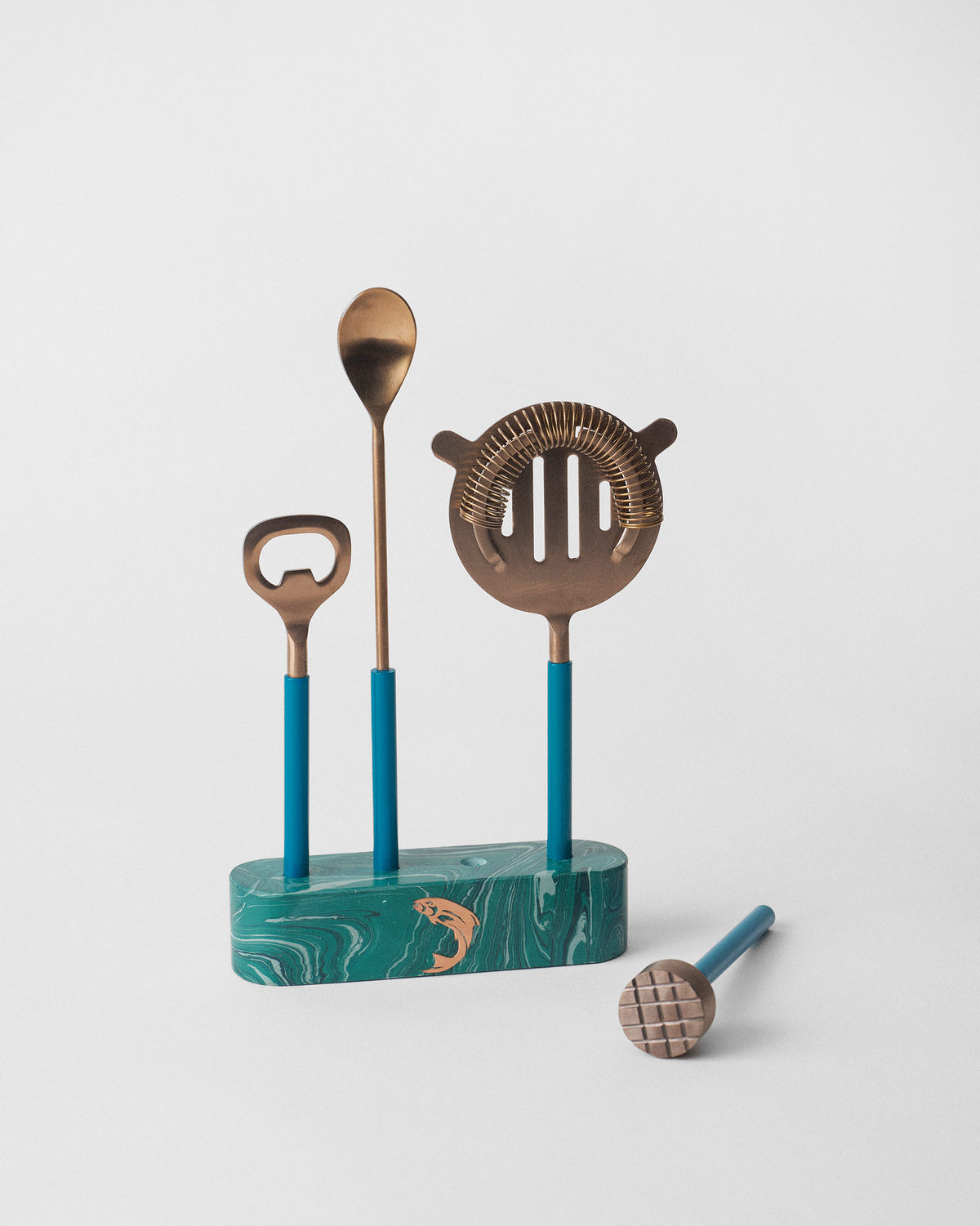 Cascade bar tools with a muddler laid beside the green marbled base.
