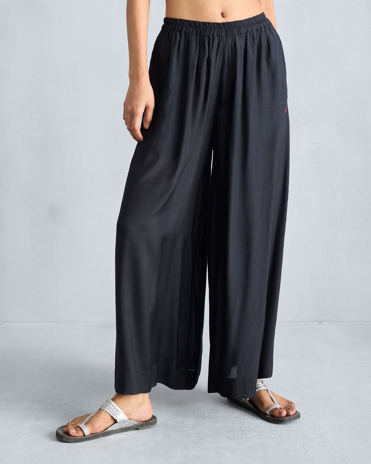 Person wearing black Classic Pyjama pants with a gathered waist and wide legs.