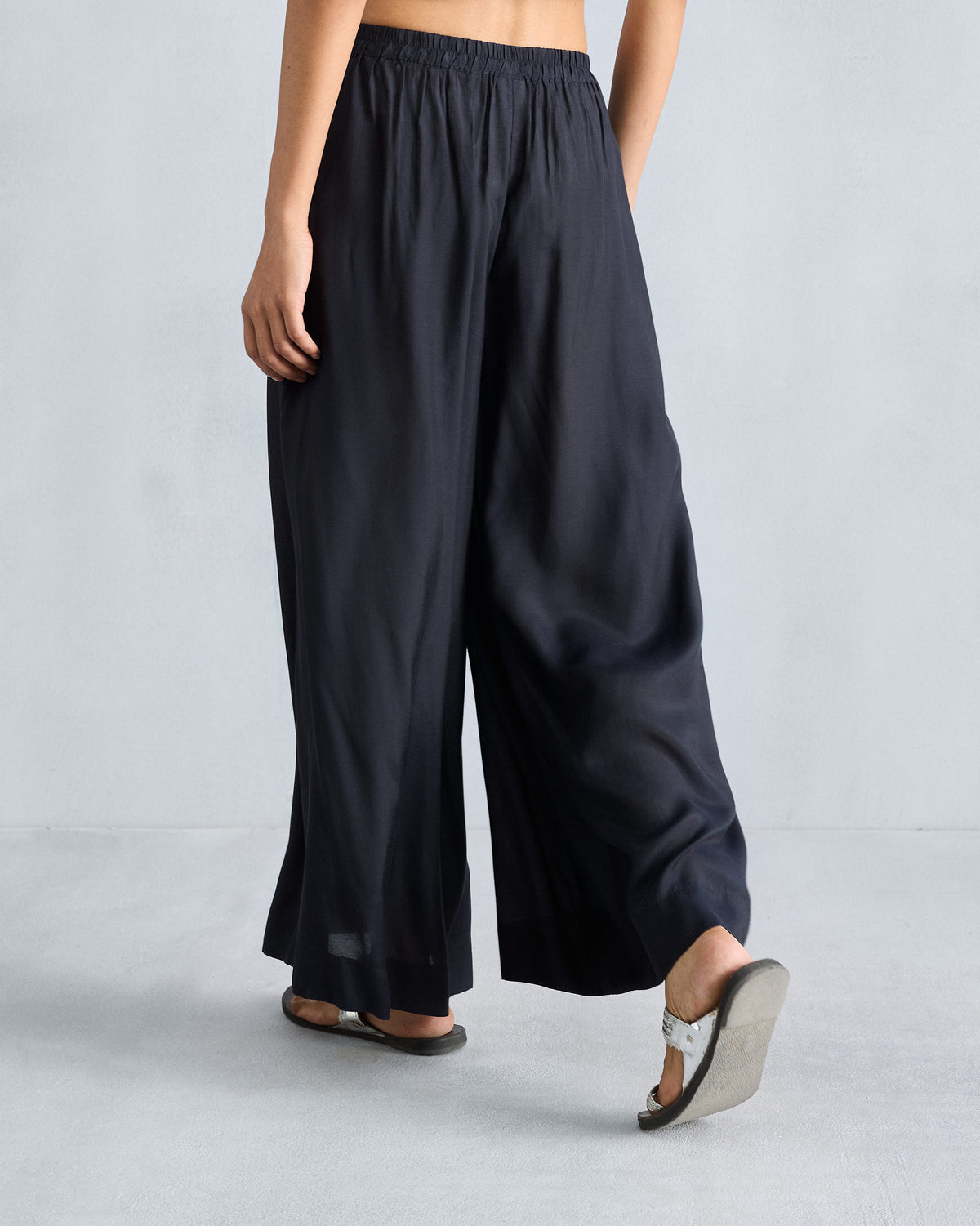 Back of black Classic Pyjama pants with a gathered waist and flowing wide legs.