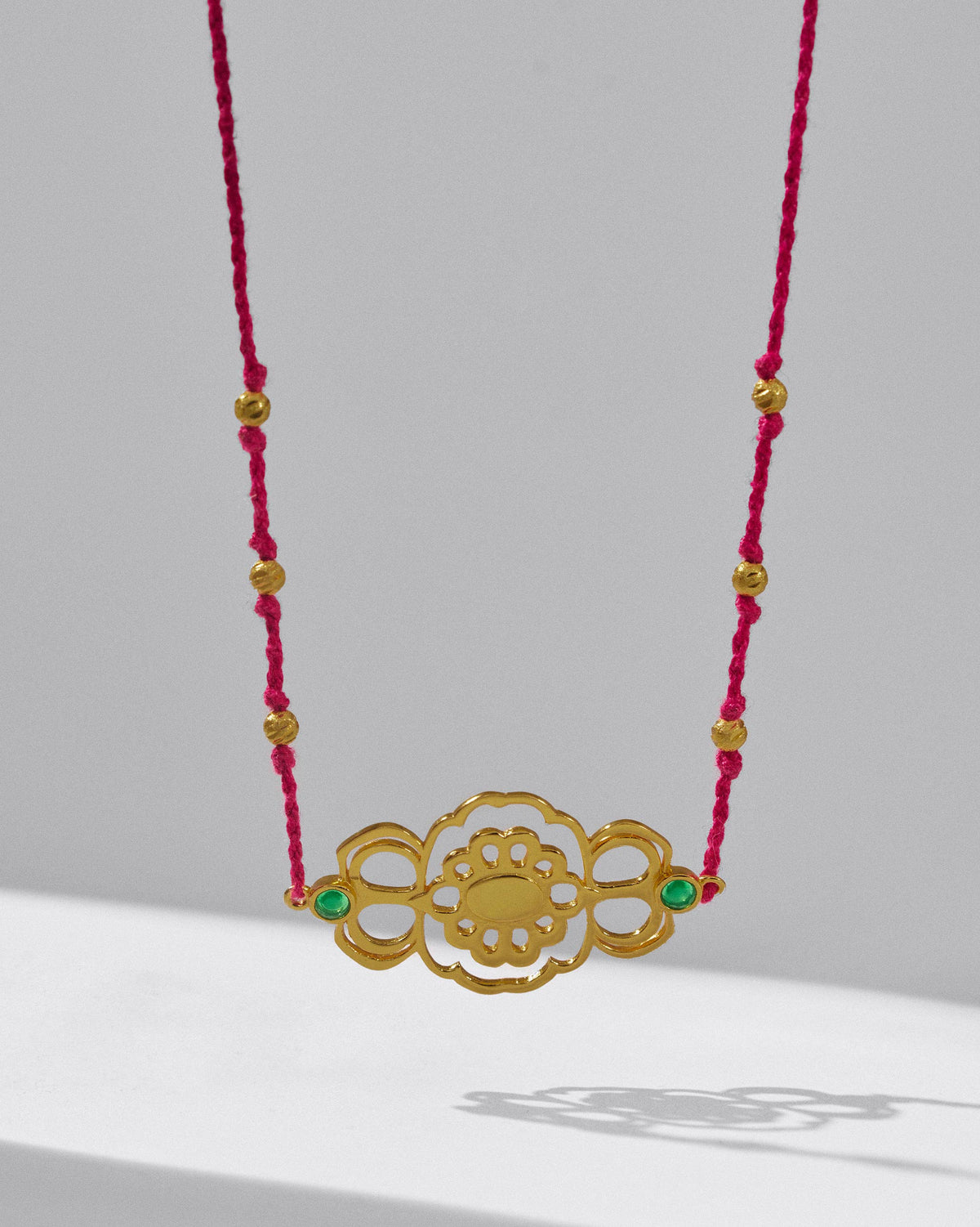 Close-up of a gold titli choker centrepiece with green stones.