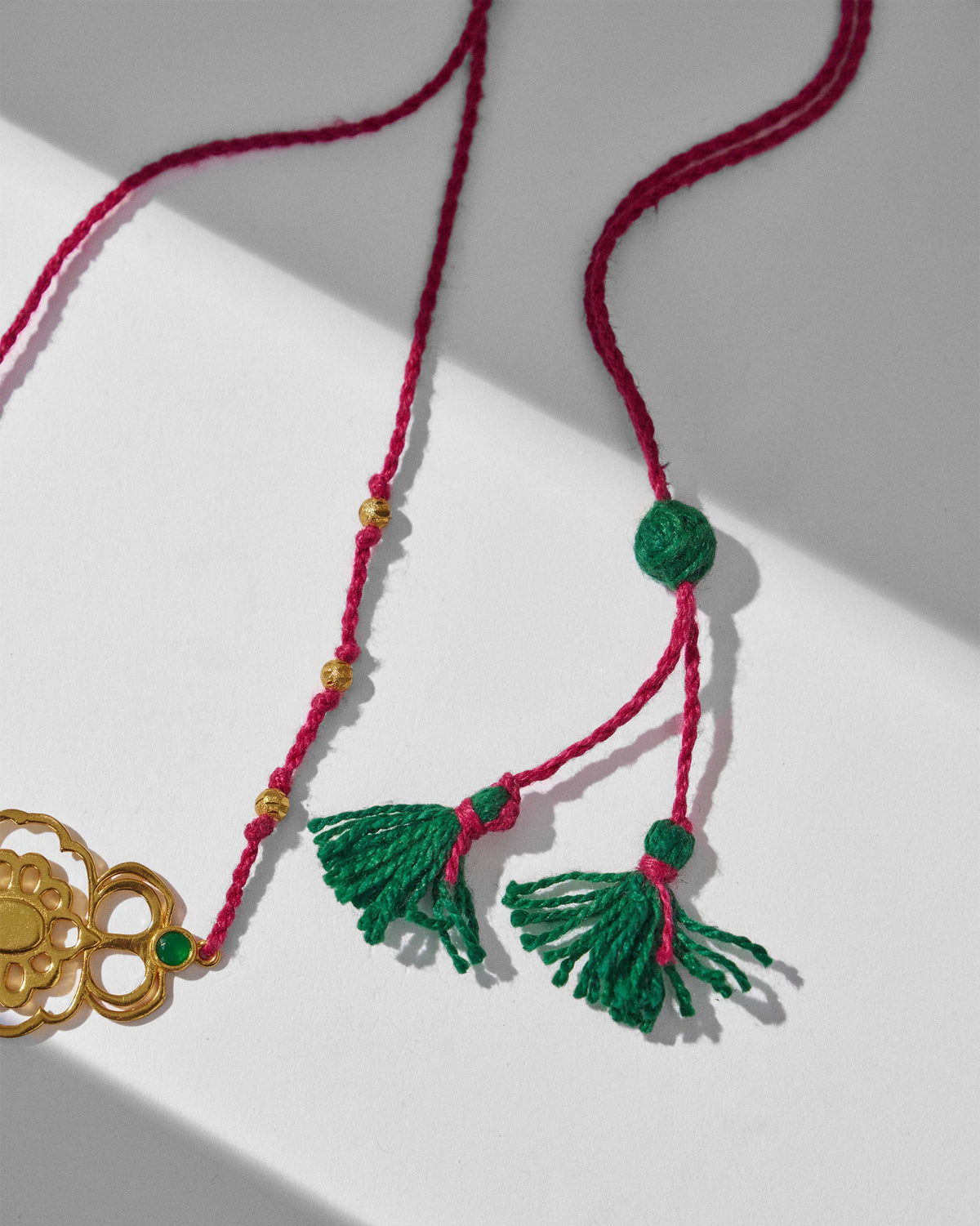 Close-up of a gold titli choker cord with green tassels.